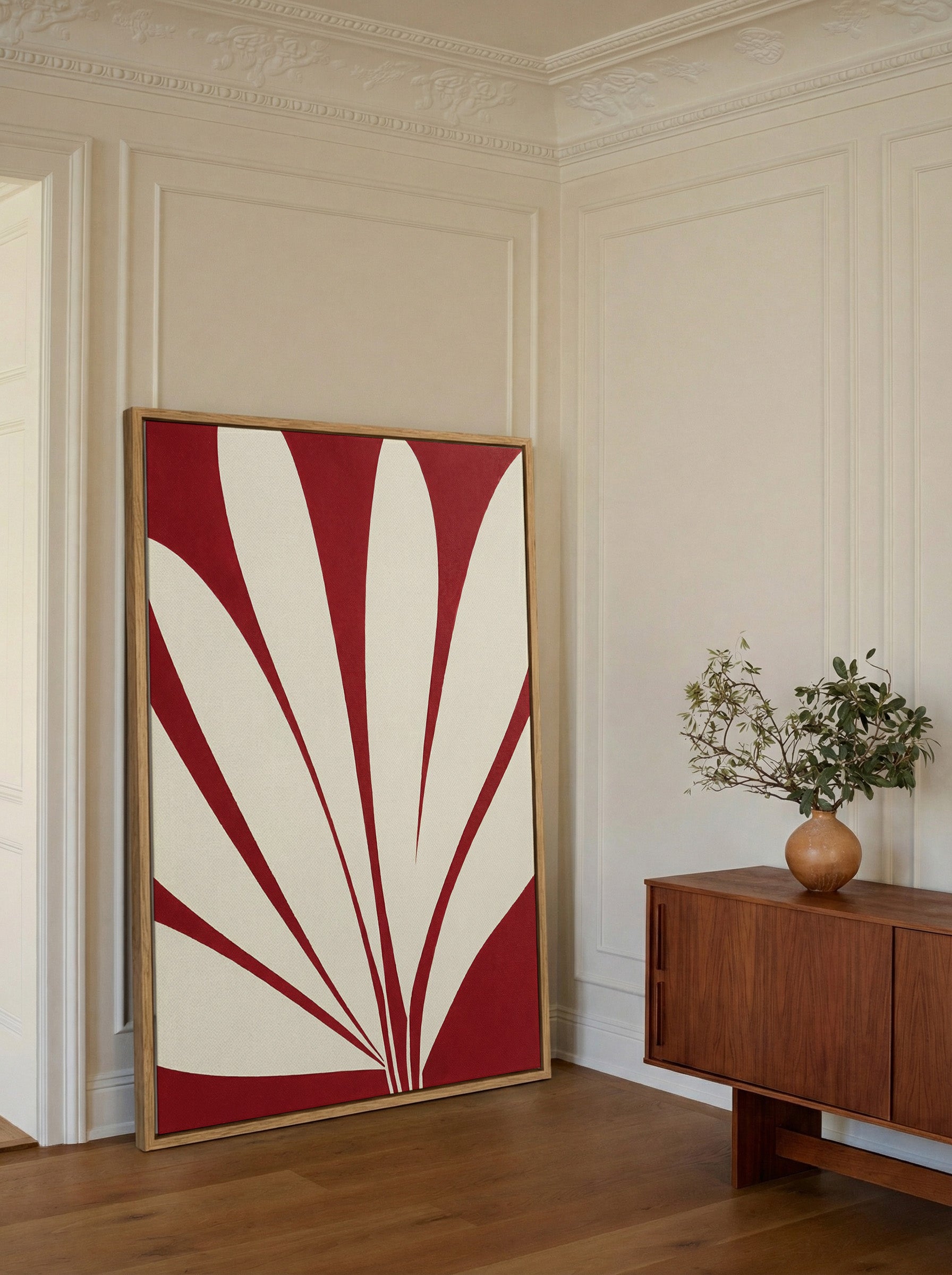 deep red and cream abstract with radiating canvas wall art in an oak frame in a styled room setting
