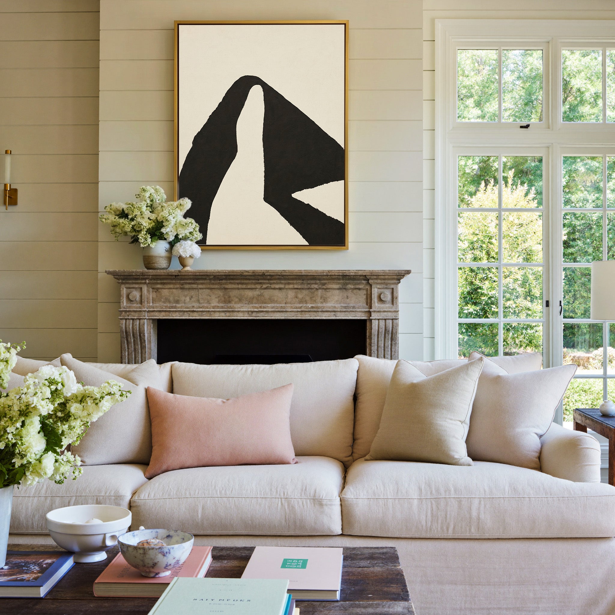 black and cream abstract with sweeping angular canvas wall art in a gold frame above a mantel