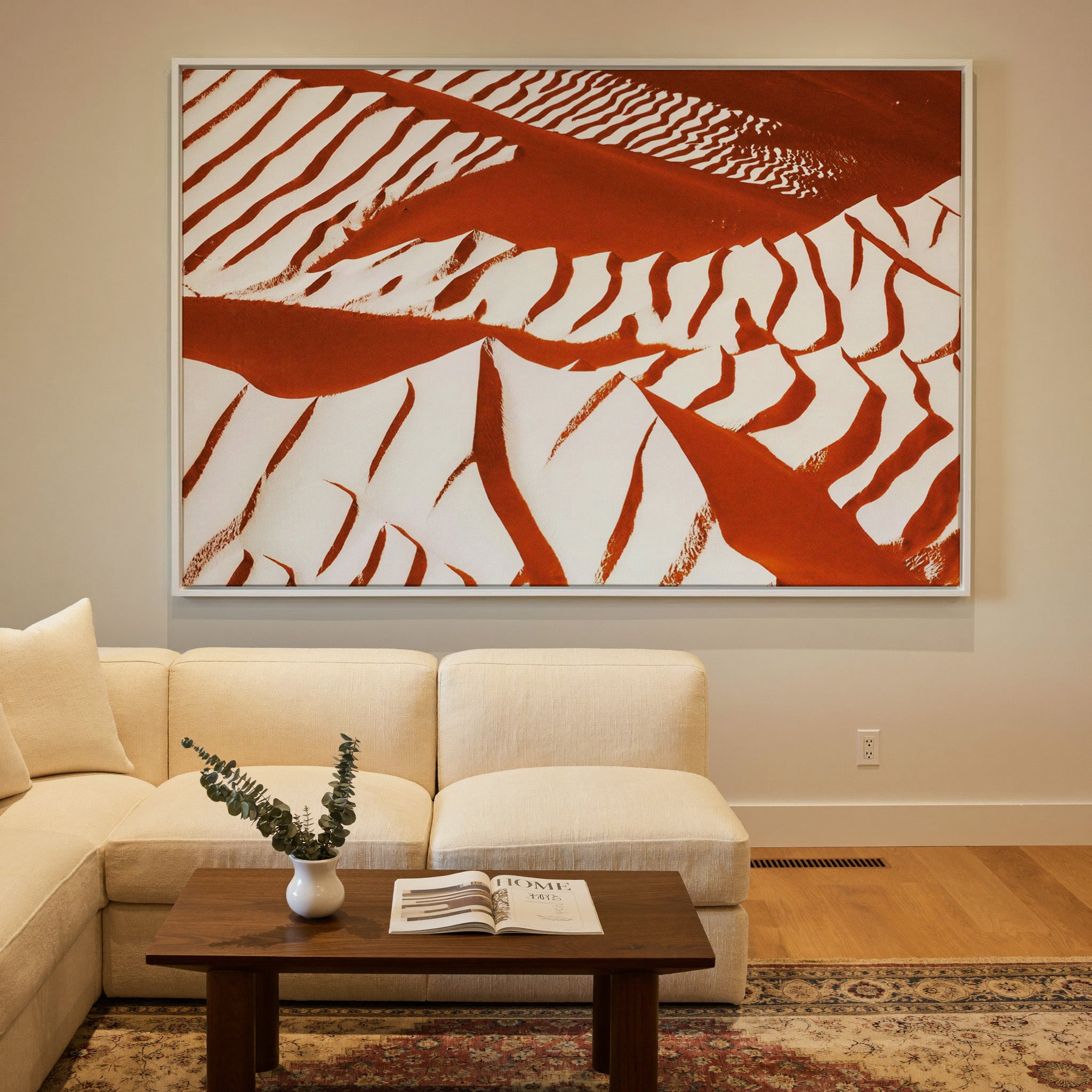 rust and cream abstract with sweeping diagonal canvas wall art in a white frame in a styled room setting