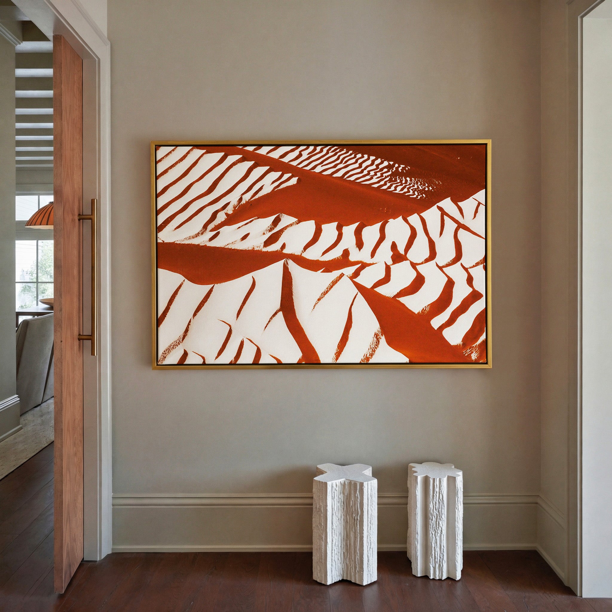 rust and cream abstract with sweeping diagonal canvas wall art in a gold frame in a styled room setting