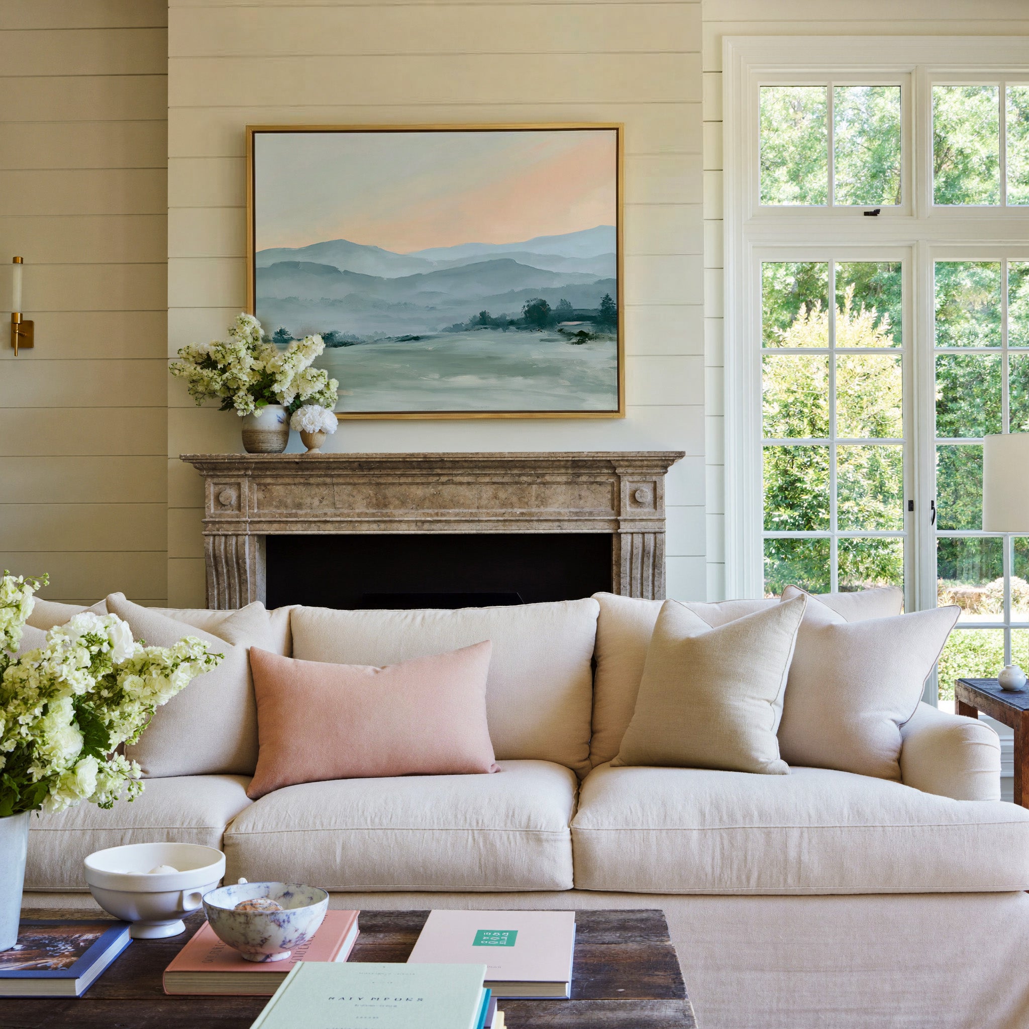 misty blue hills with a peach sky canvas wall art in a gold frame above a mantel