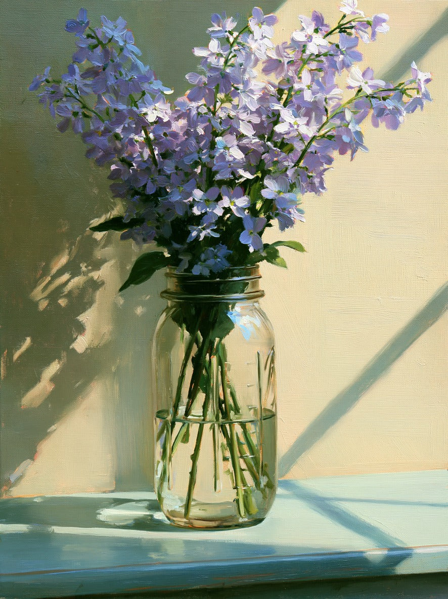 Pale lavender flowers in a clear glass jar with long diagonal shadows on a sage wall