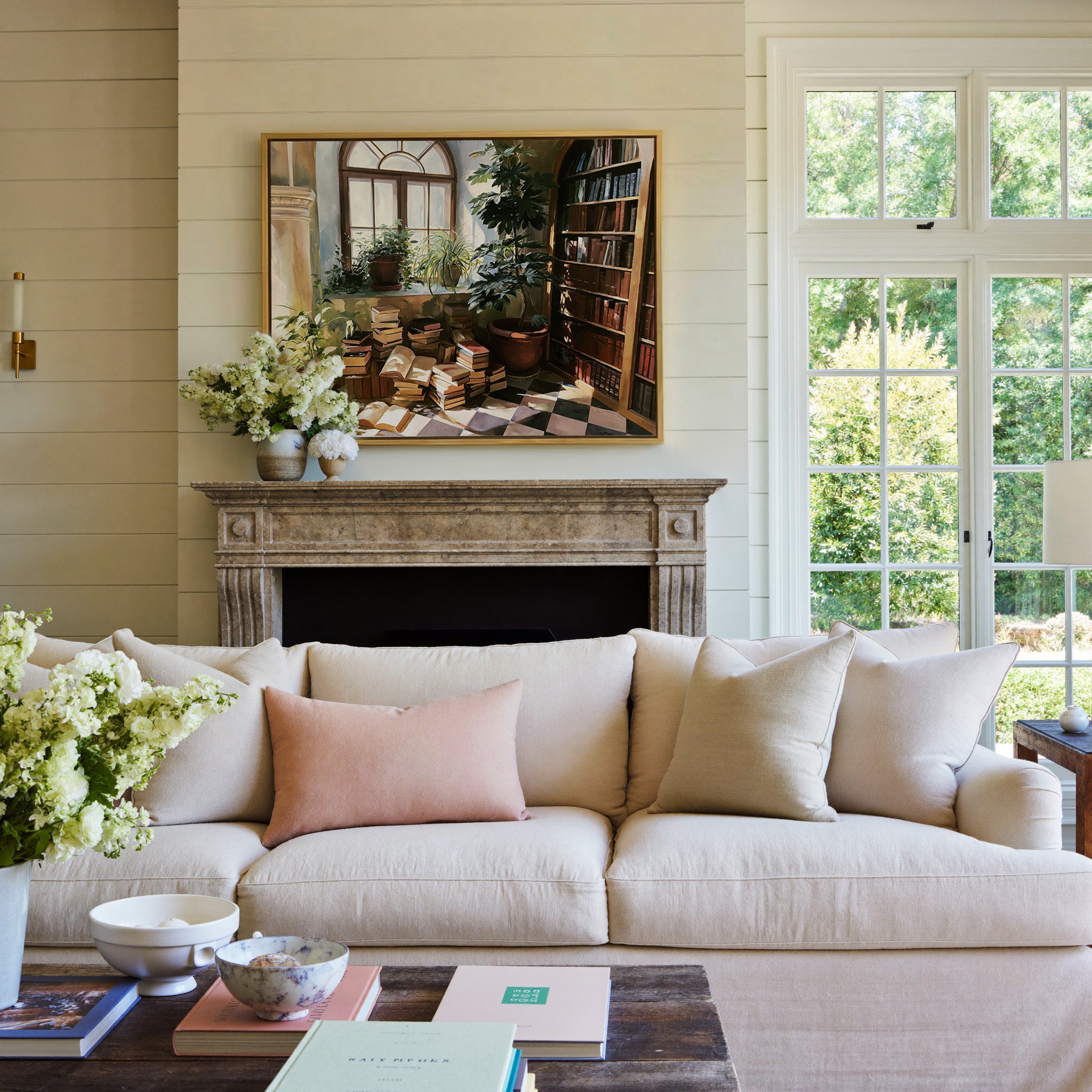 arched window with stacked books and potted canvas wall art in a gold frame above a mantel