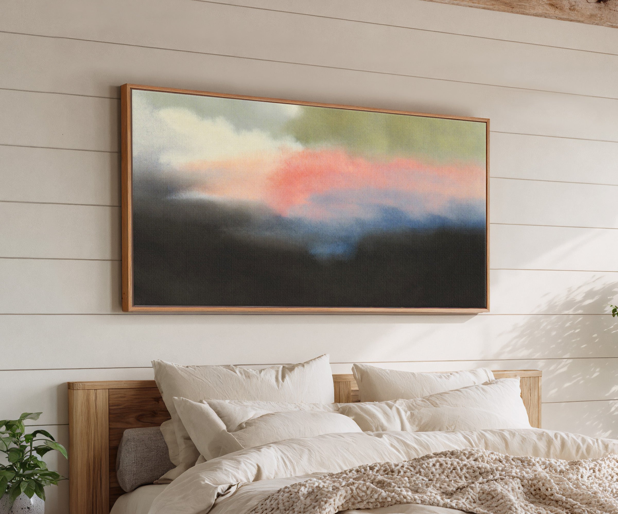 soft pink and blue abstract with dark grounding canvas wall art in an oak frame above a bed