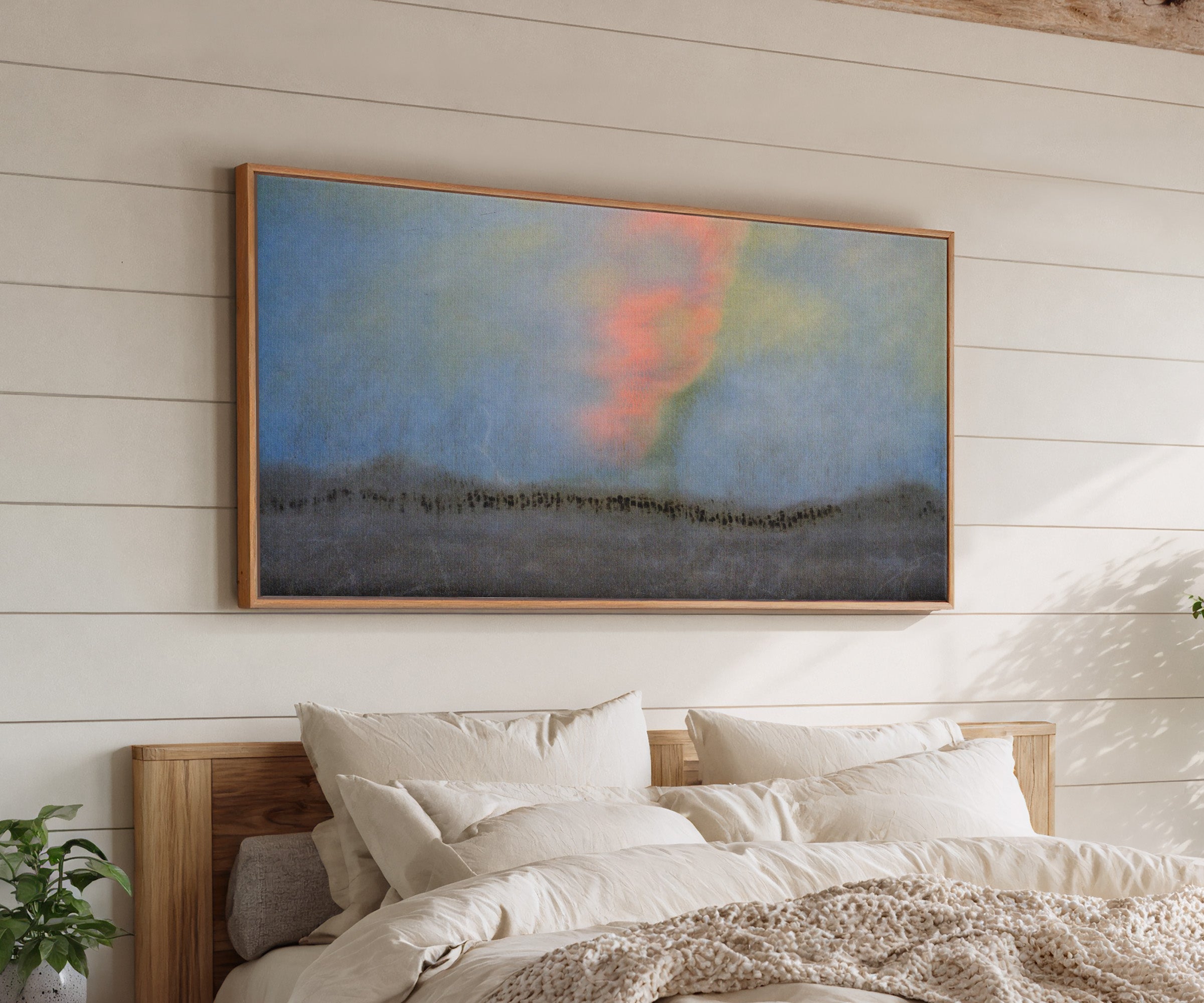 soft blue abstract with coral glow and dark canvas wall art in an oak frame above a bed