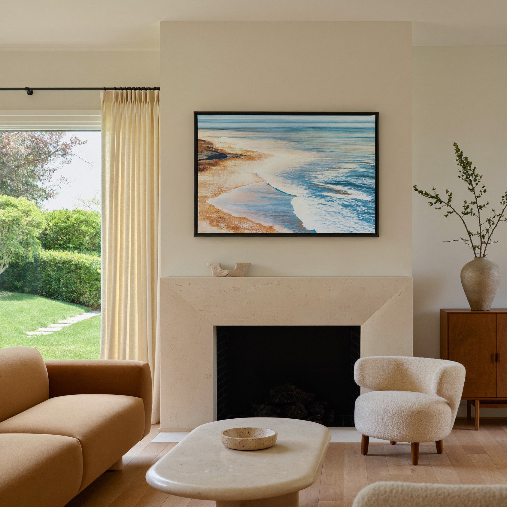 blue water meeting warm sand canvas wall art in a black frame above a mantel