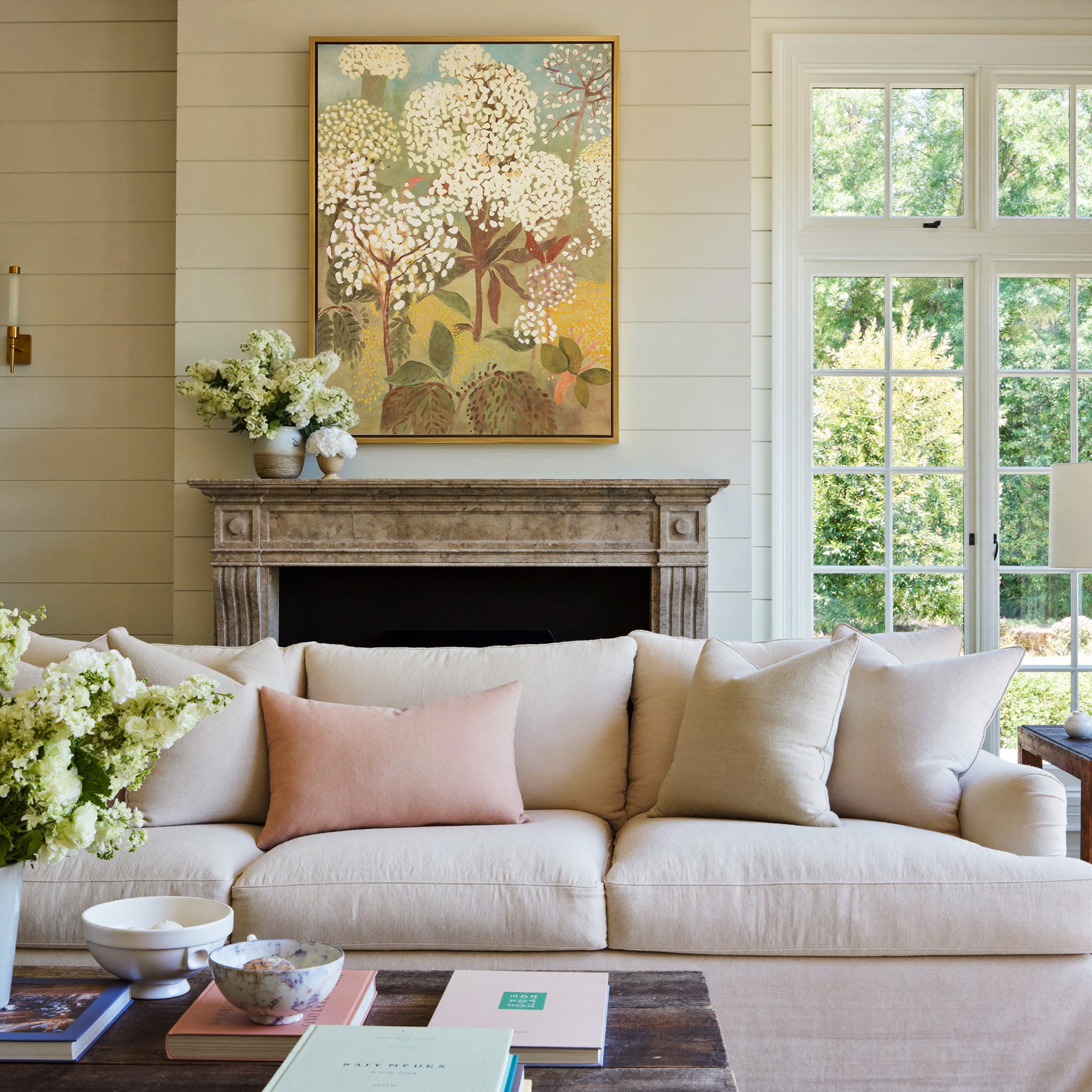 soft floral trees with cream blossoms and muted canvas wall art in a gold frame above a mantel