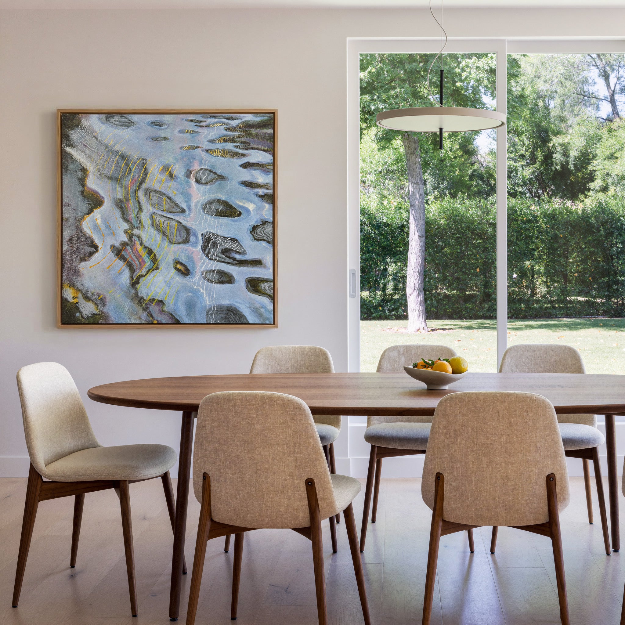blue gray abstract with dark oval forms and canvas wall art in an oak frame in a dining room