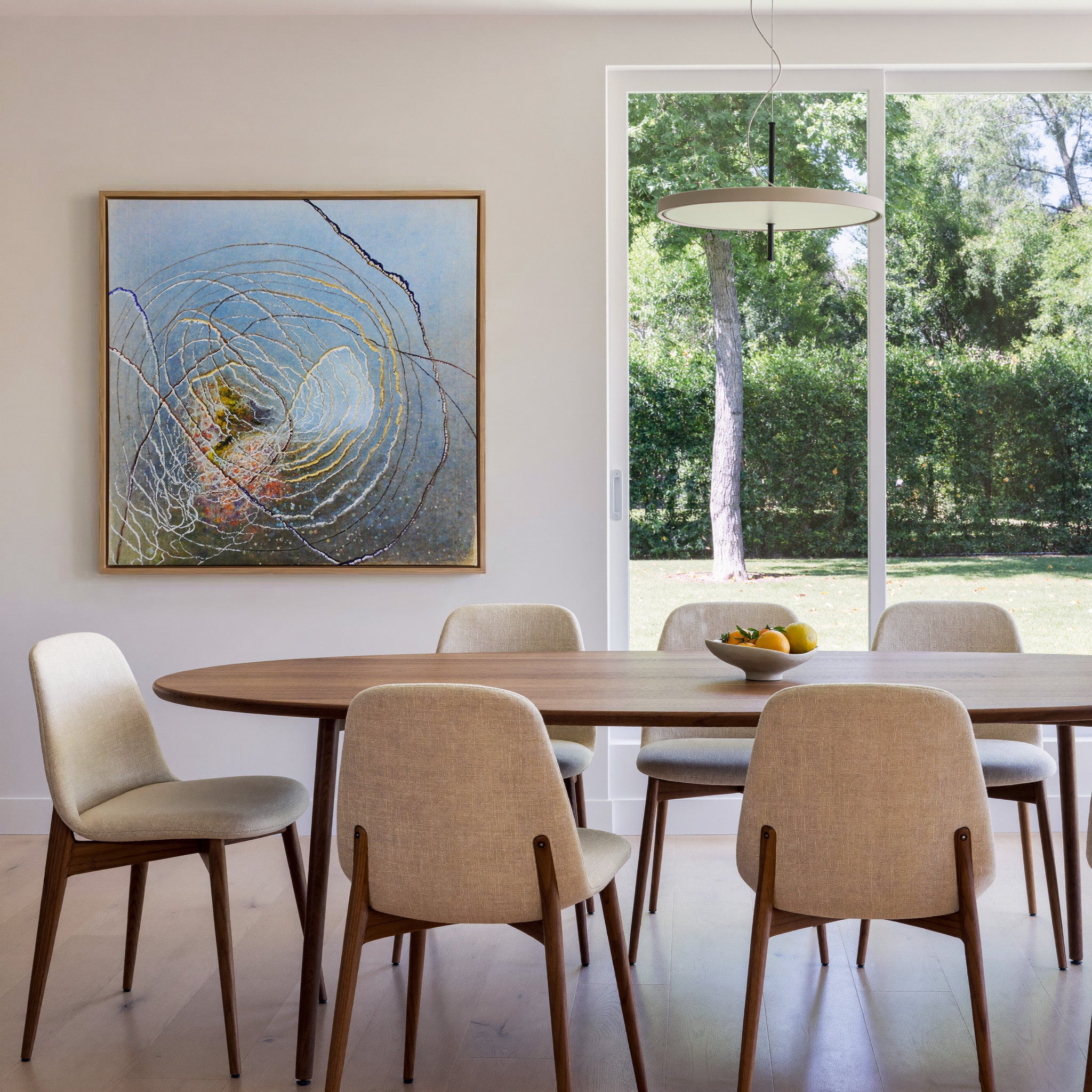 blue abstract with concentric rings and dark canvas wall art in an oak frame in a dining room