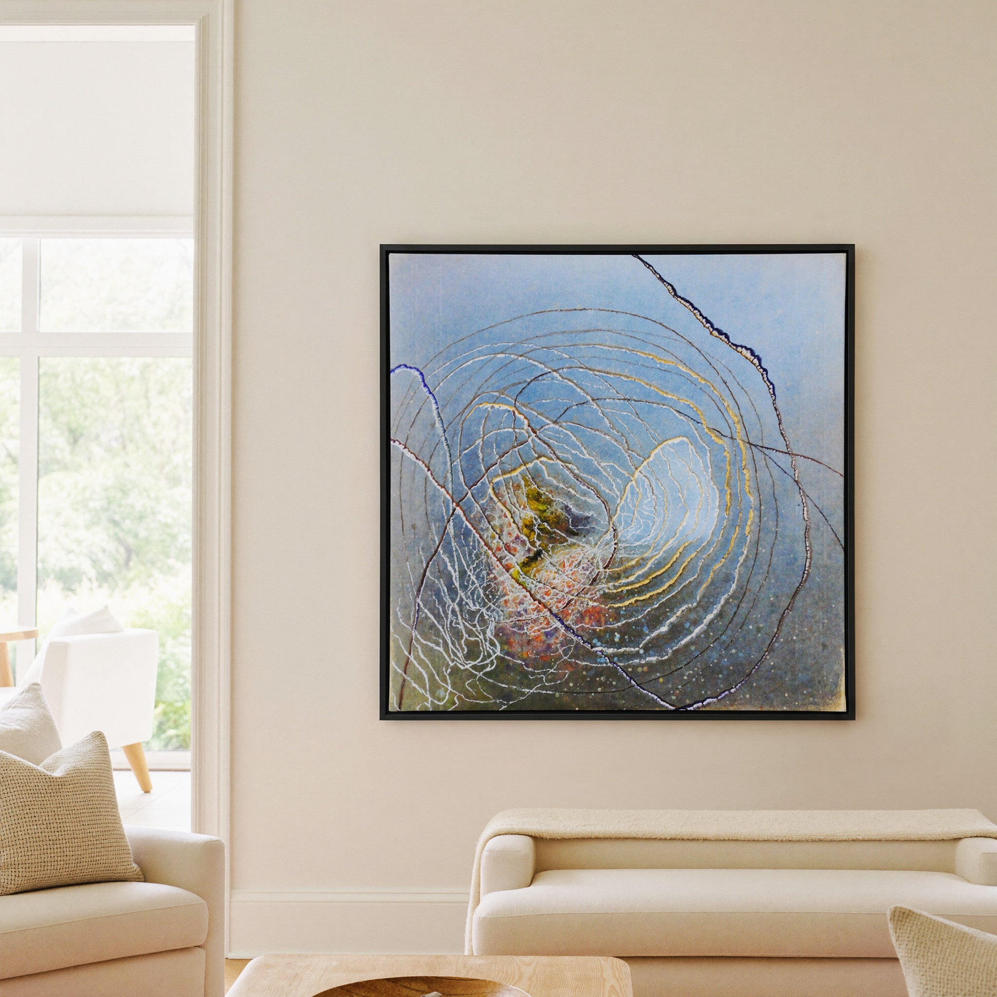 blue abstract with concentric rings and dark canvas wall art in a black frame in a living room