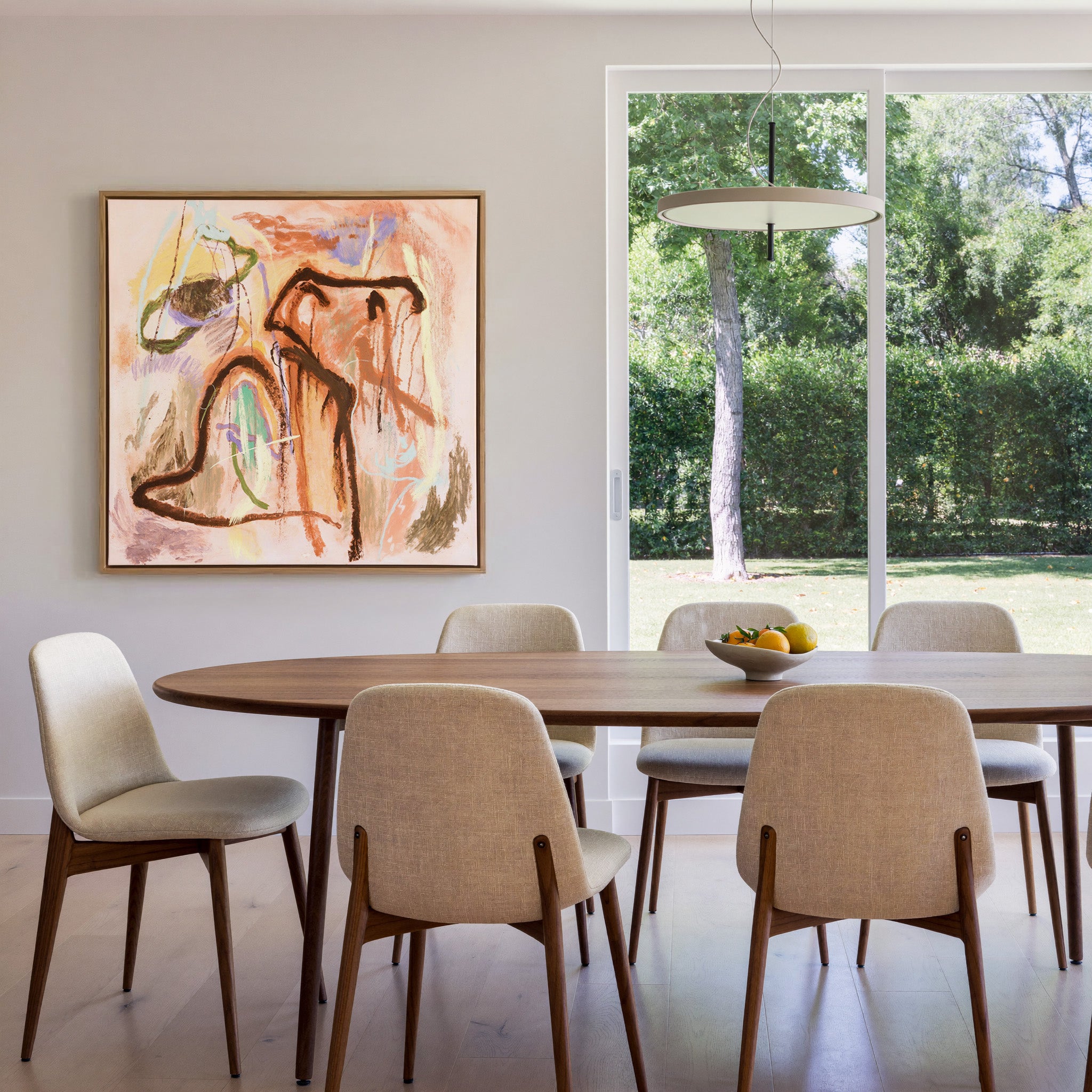 warm peach abstract with dark looping lines and canvas wall art in an oak frame in a dining room