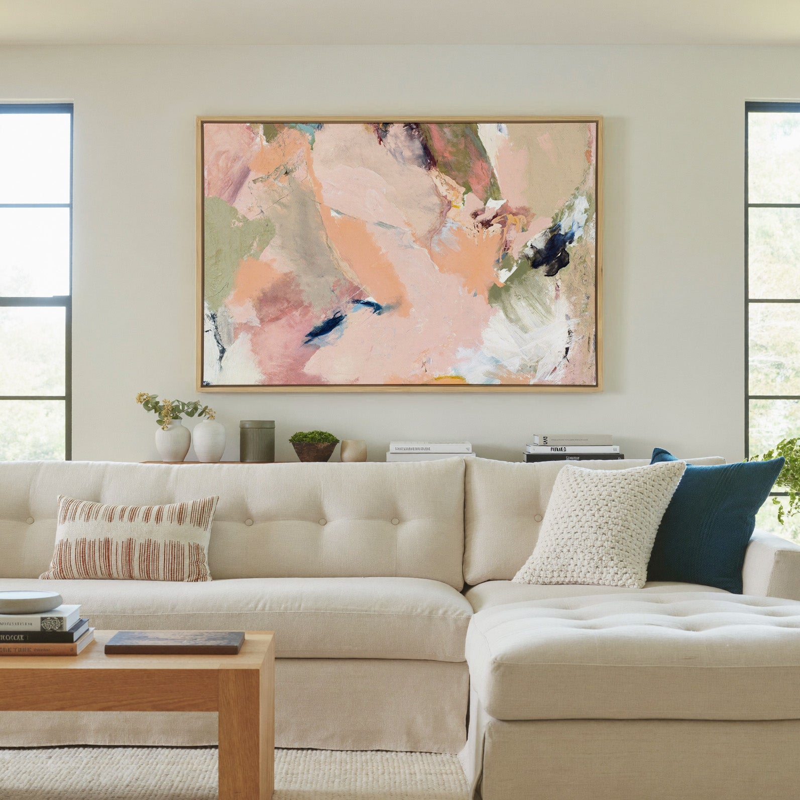 soft blush, peach, sage, and navy abstract canvas wall art in a natural wood frame in a living room