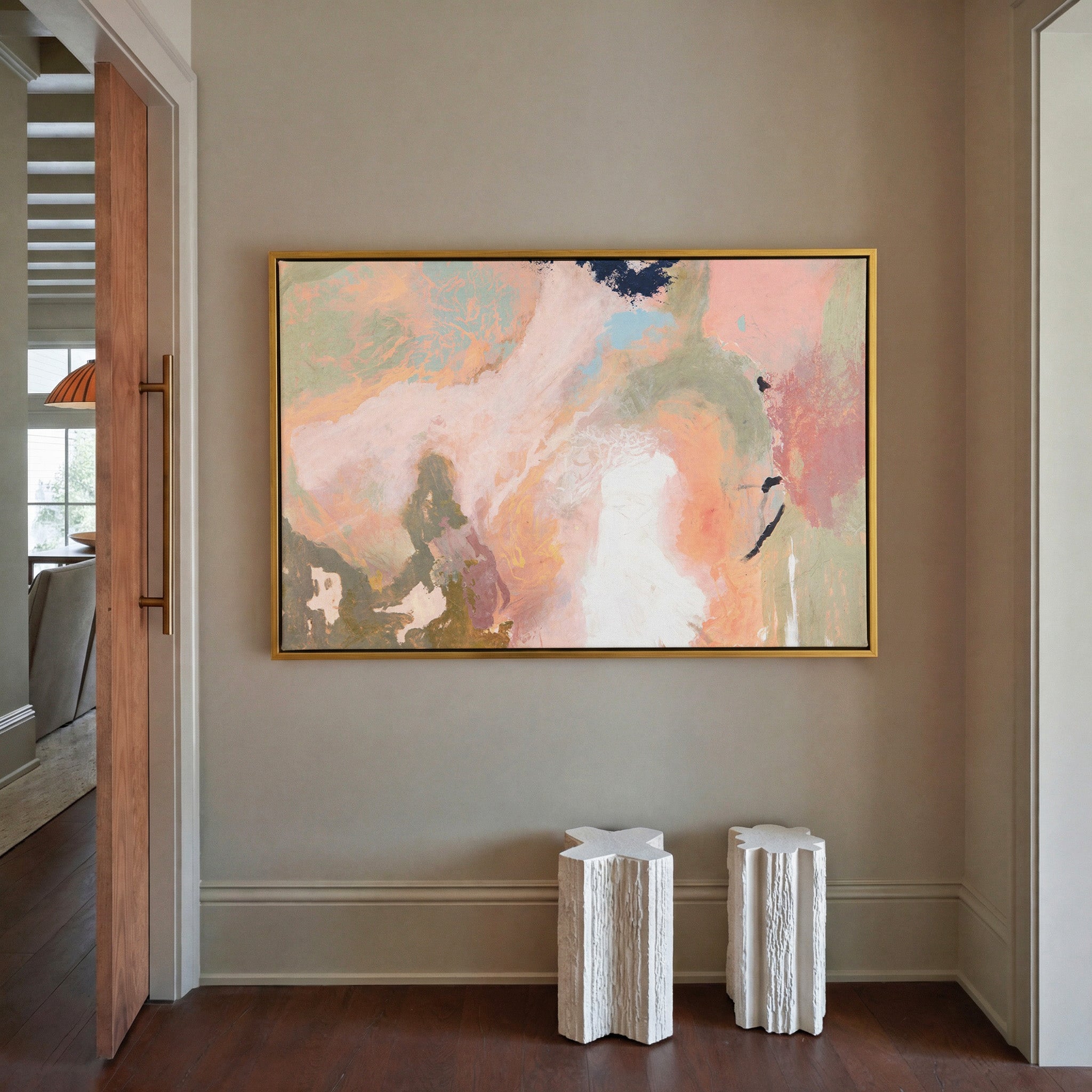 soft peach, sage, and cream abstract with dark canvas wall art in a gold frame in a styled room setting