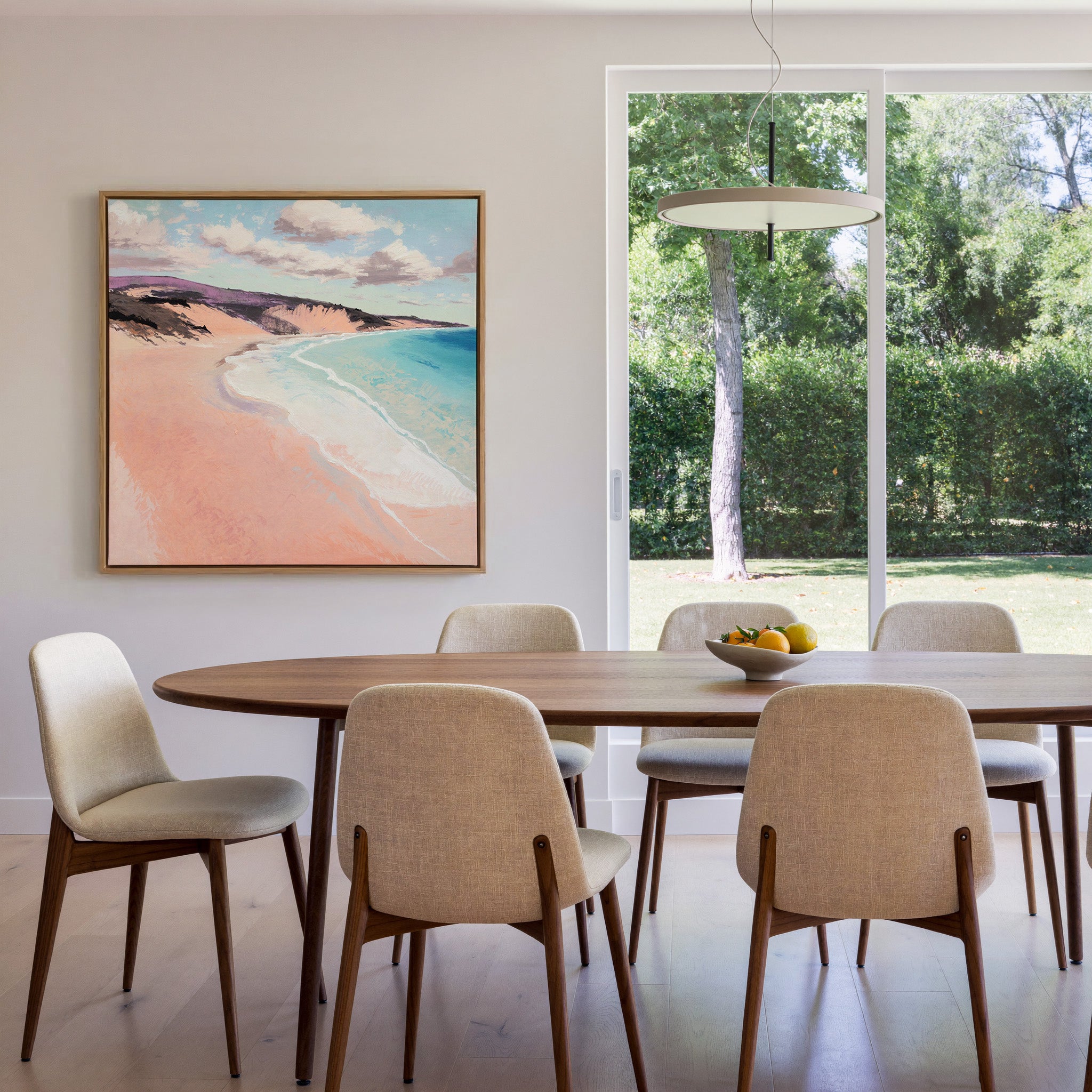 soft peach beach with turquoise water and canvas wall art in an oak frame in a dining room