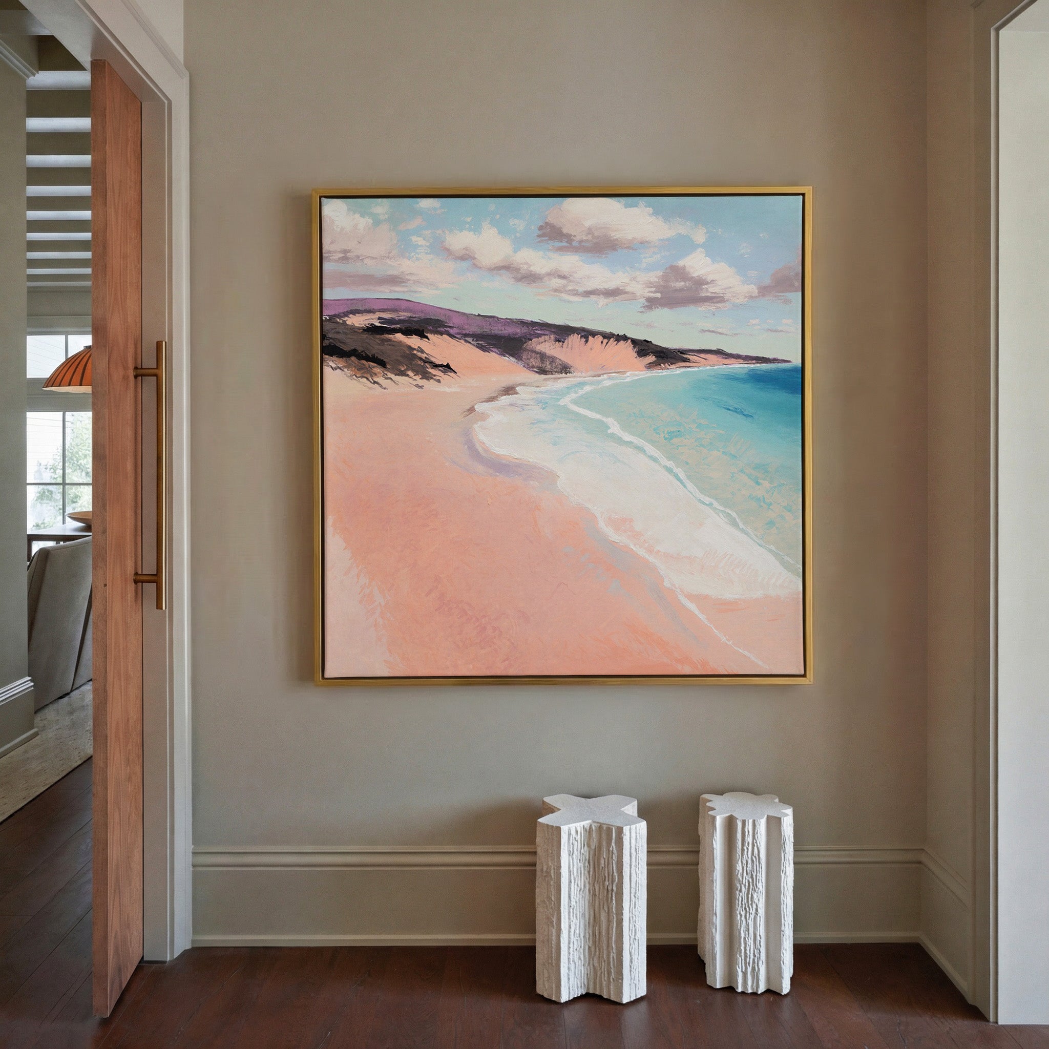 soft peach beach with turquoise water and canvas wall art in a gold frame in a styled room setting