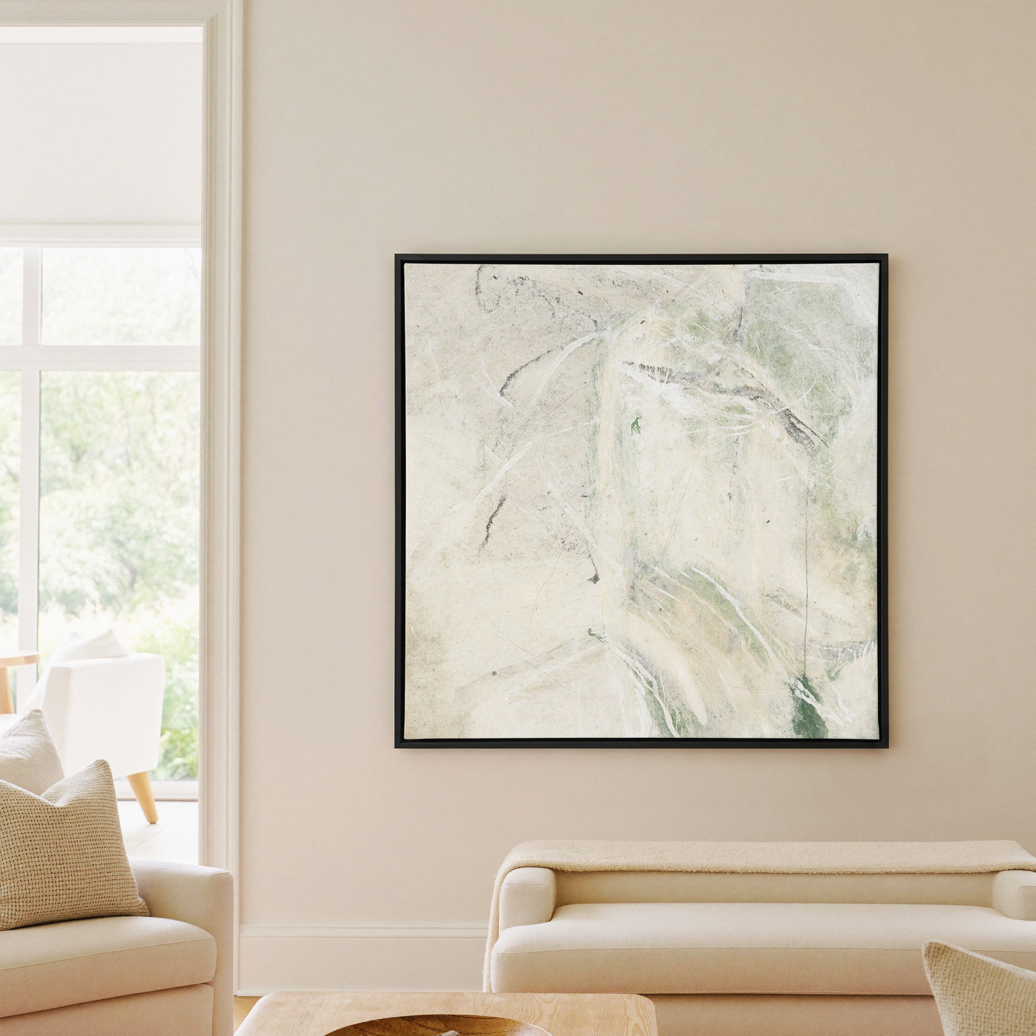soft cream abstract with pale green sweeps and canvas wall art in a black frame in a living room