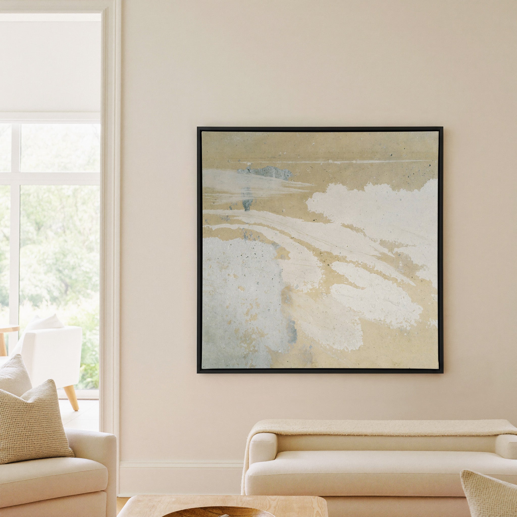 cream and sand abstract with pale blue streaks canvas wall art in a black frame in a living room