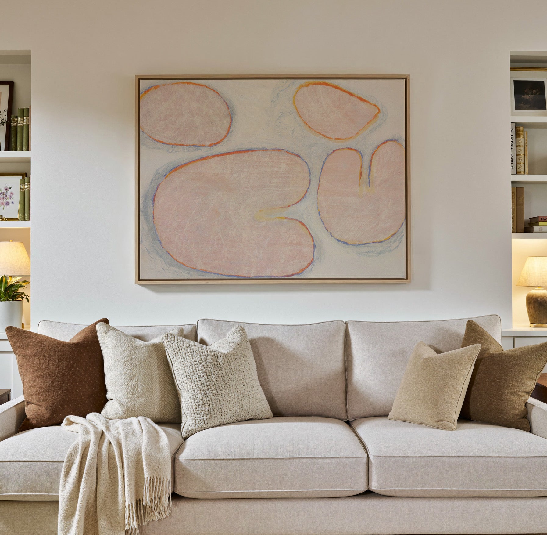 pale blush abstract with rounded canvas wall art in a natural wood frame in a styled room setting