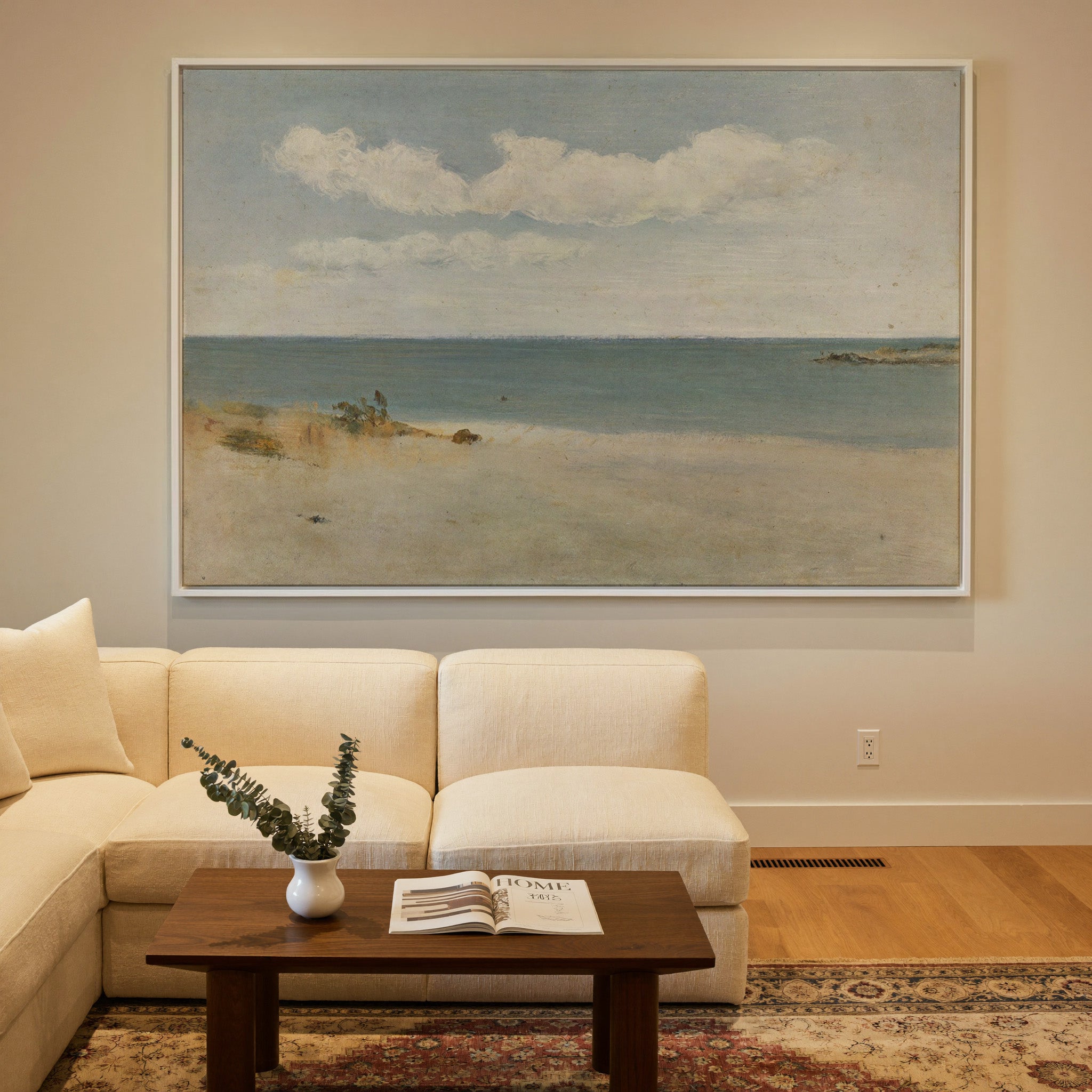 pale beach, blue green water, and broad white canvas wall art in a white frame in a styled room setting