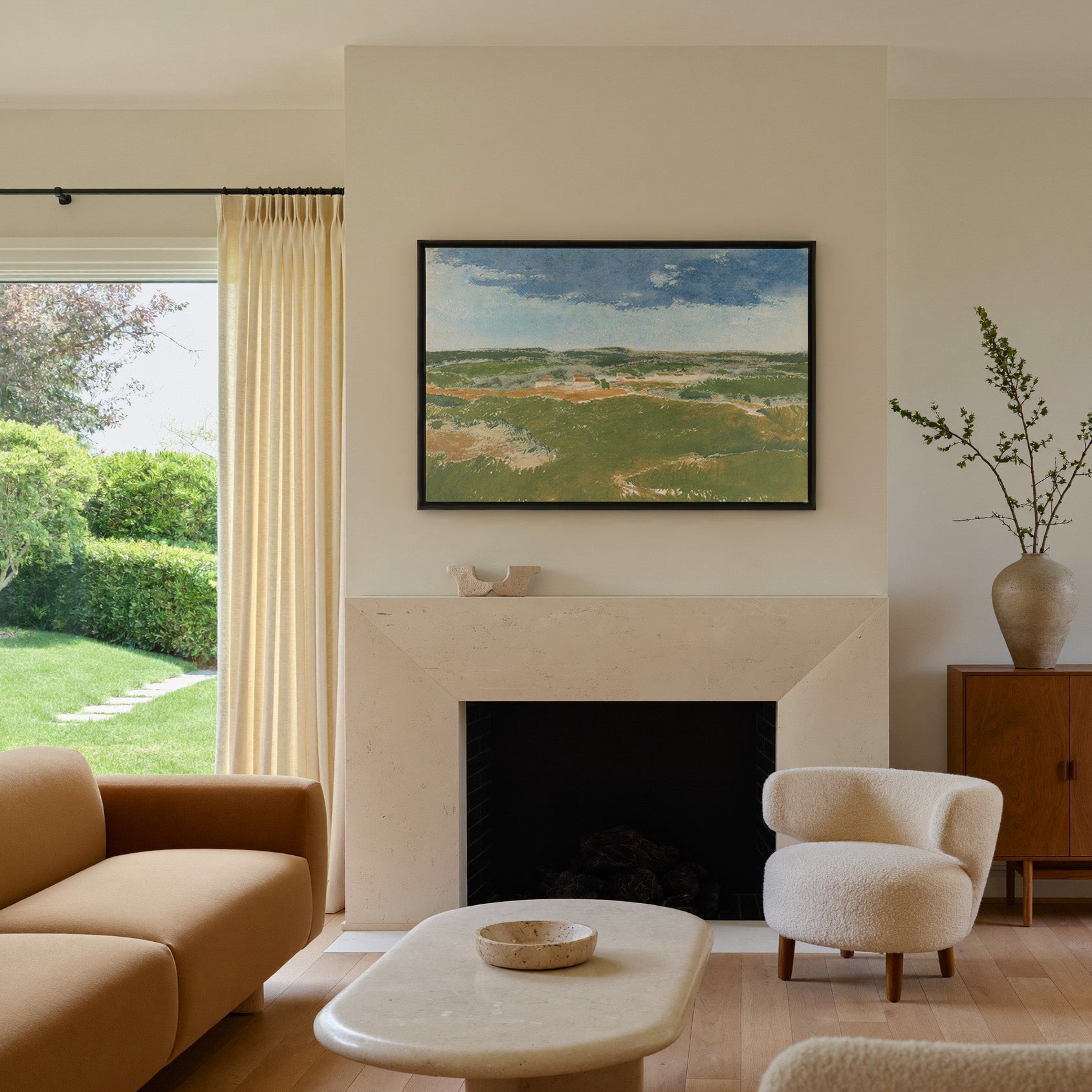 green dunes under a broad blue sky canvas wall art in a black frame above a mantel