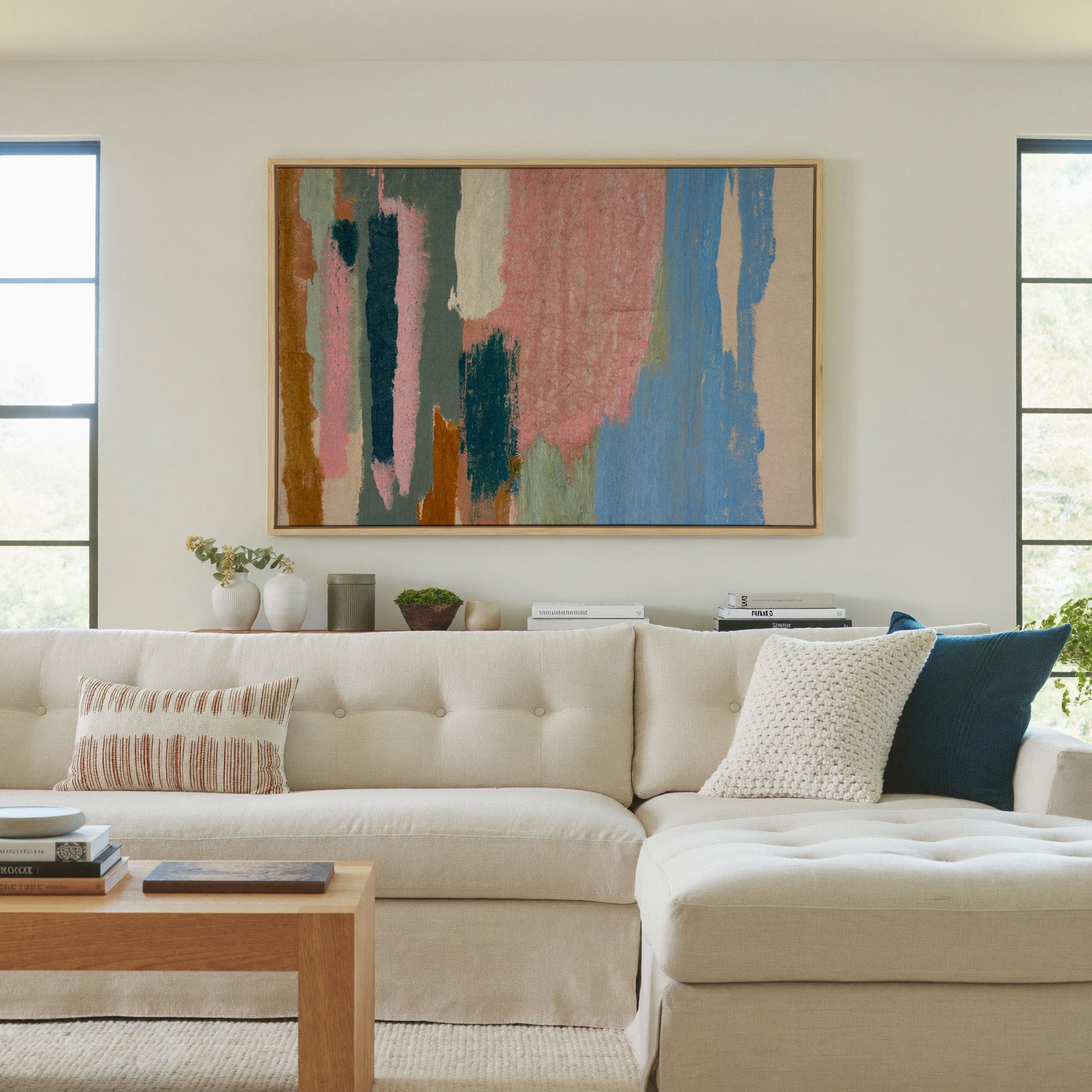 vertical abstract with pink, blue, teal, and canvas wall art in a natural wood frame in a living room