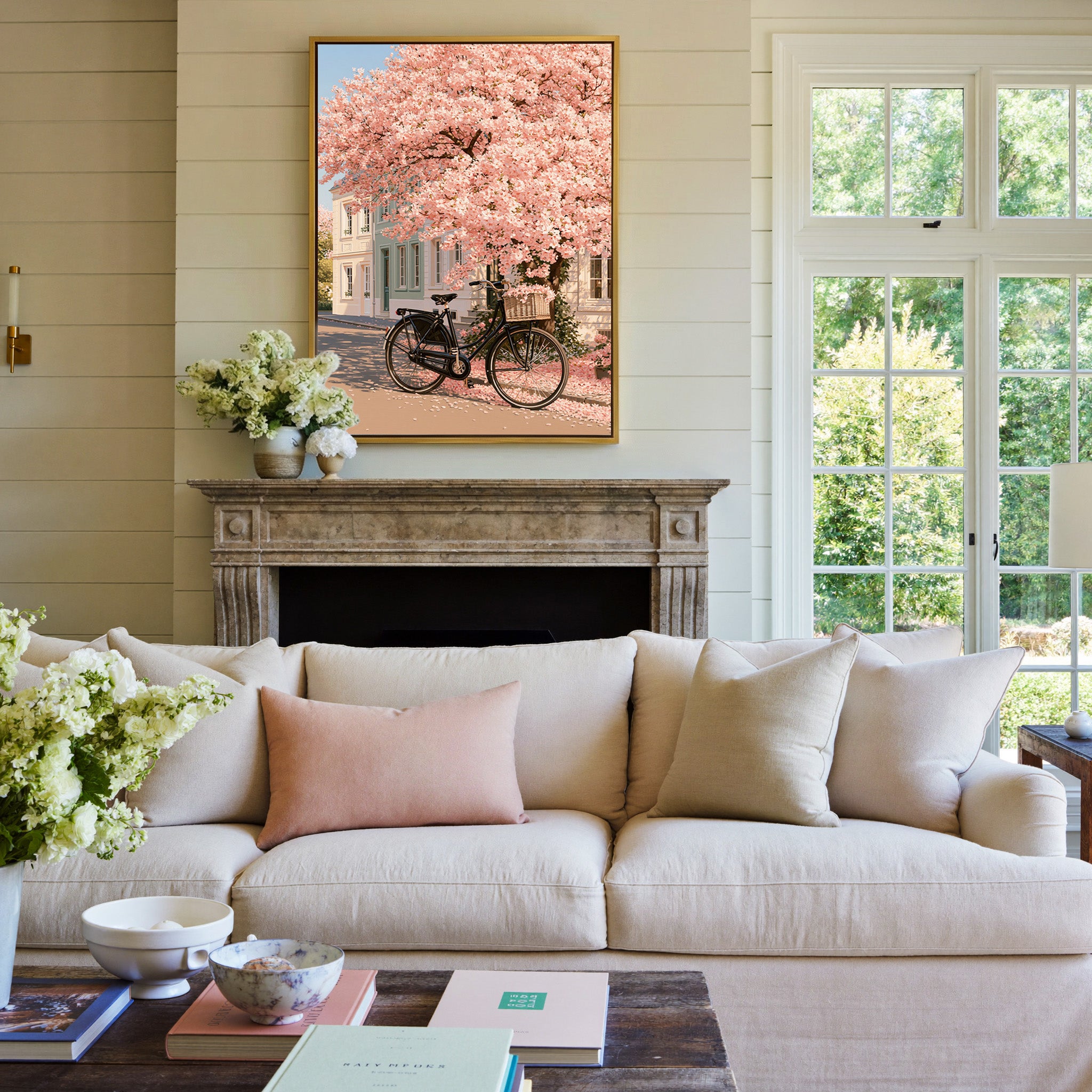 black bicycle beneath pink blossoms canvas wall art in a gold frame above a mantel