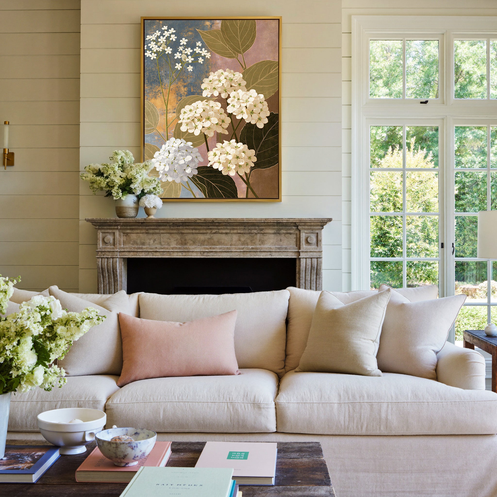 white hydrangea clusters with olive leaves on canvas wall art in a gold frame above a mantel