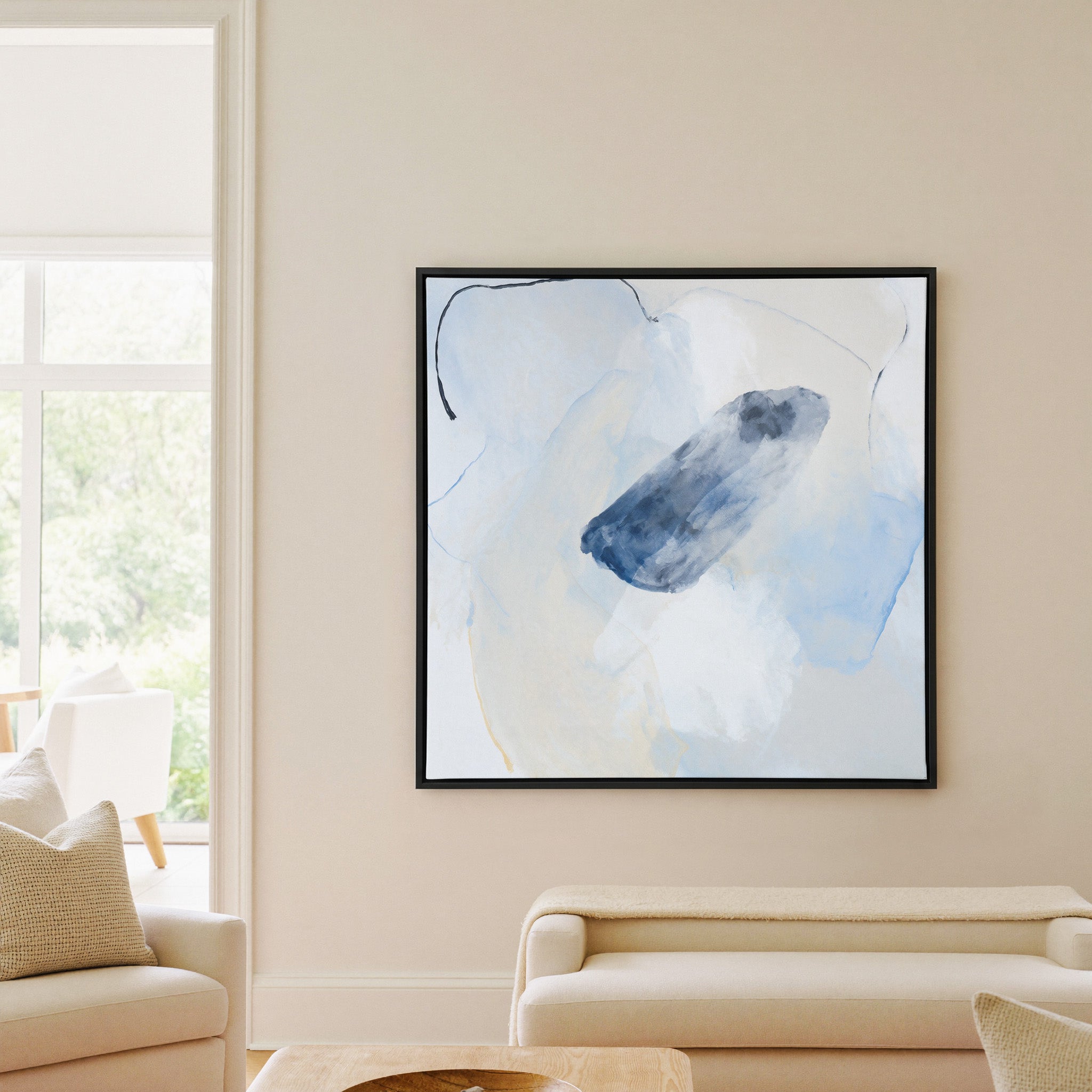 soft blue and ivory abstract with a dark indigo canvas wall art in a black frame in a living room