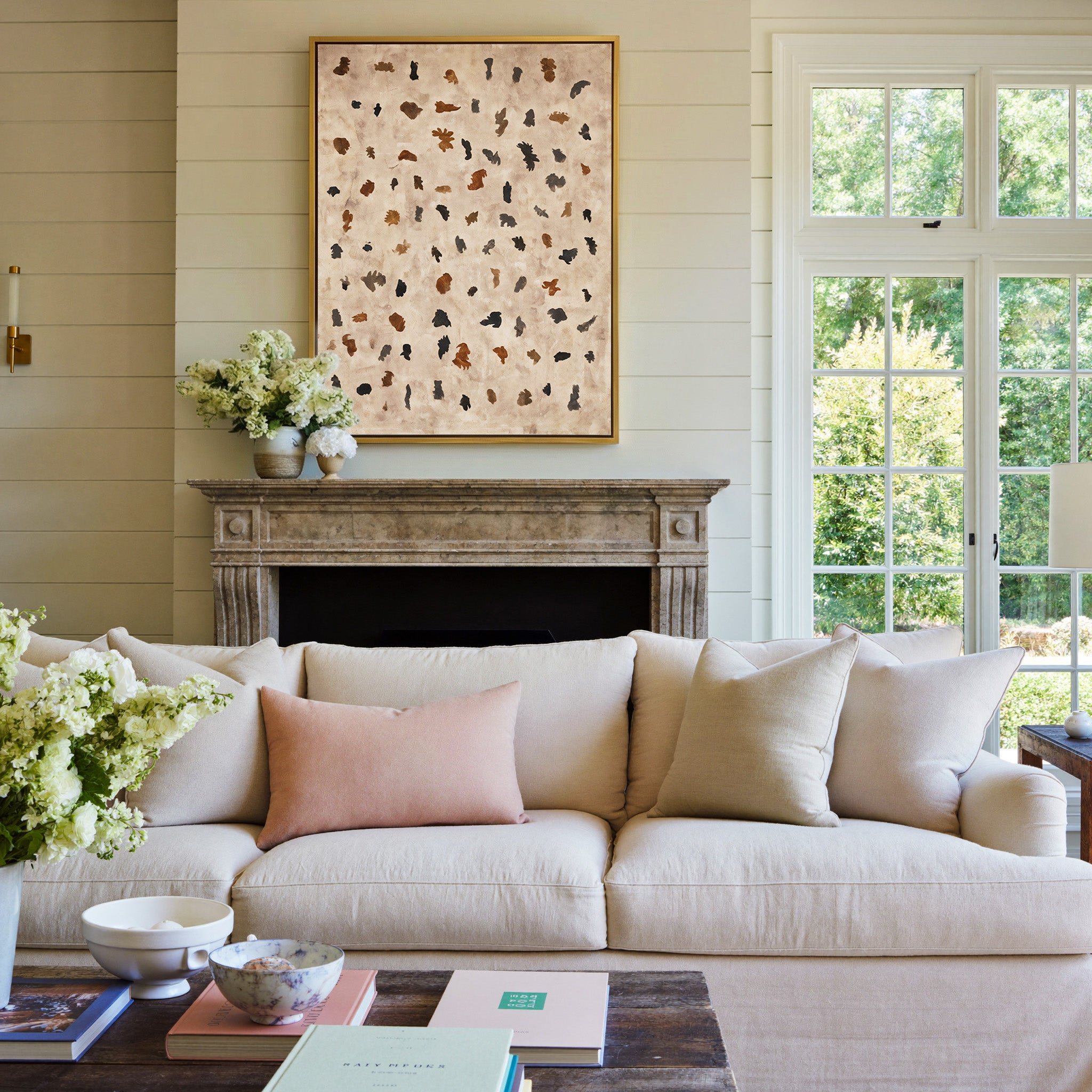 beige abstract with scattered black and rust canvas wall art in a gold frame above a mantel
