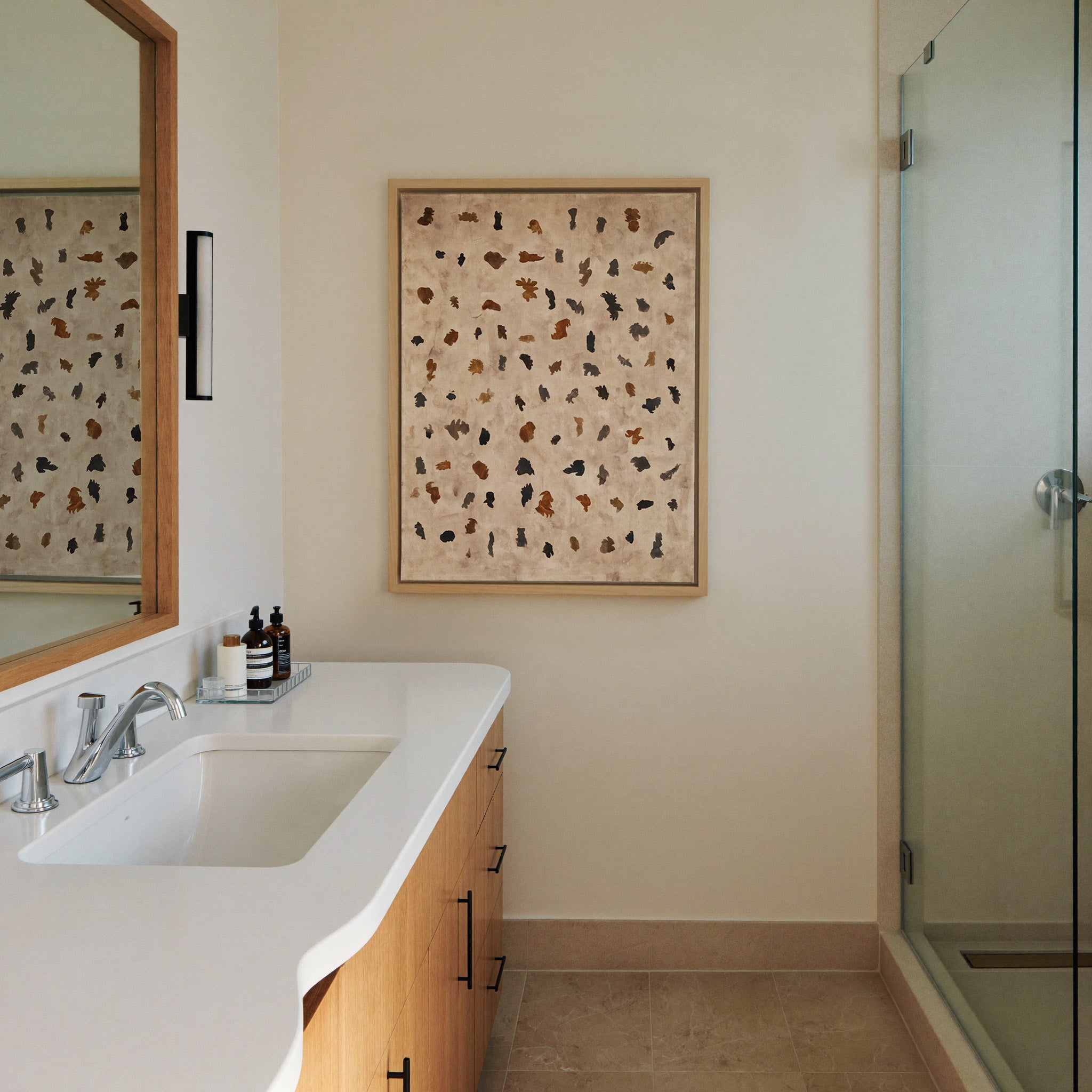 beige abstract with scattered black and rust canvas wall art in a natural wood frame in a styled room setting