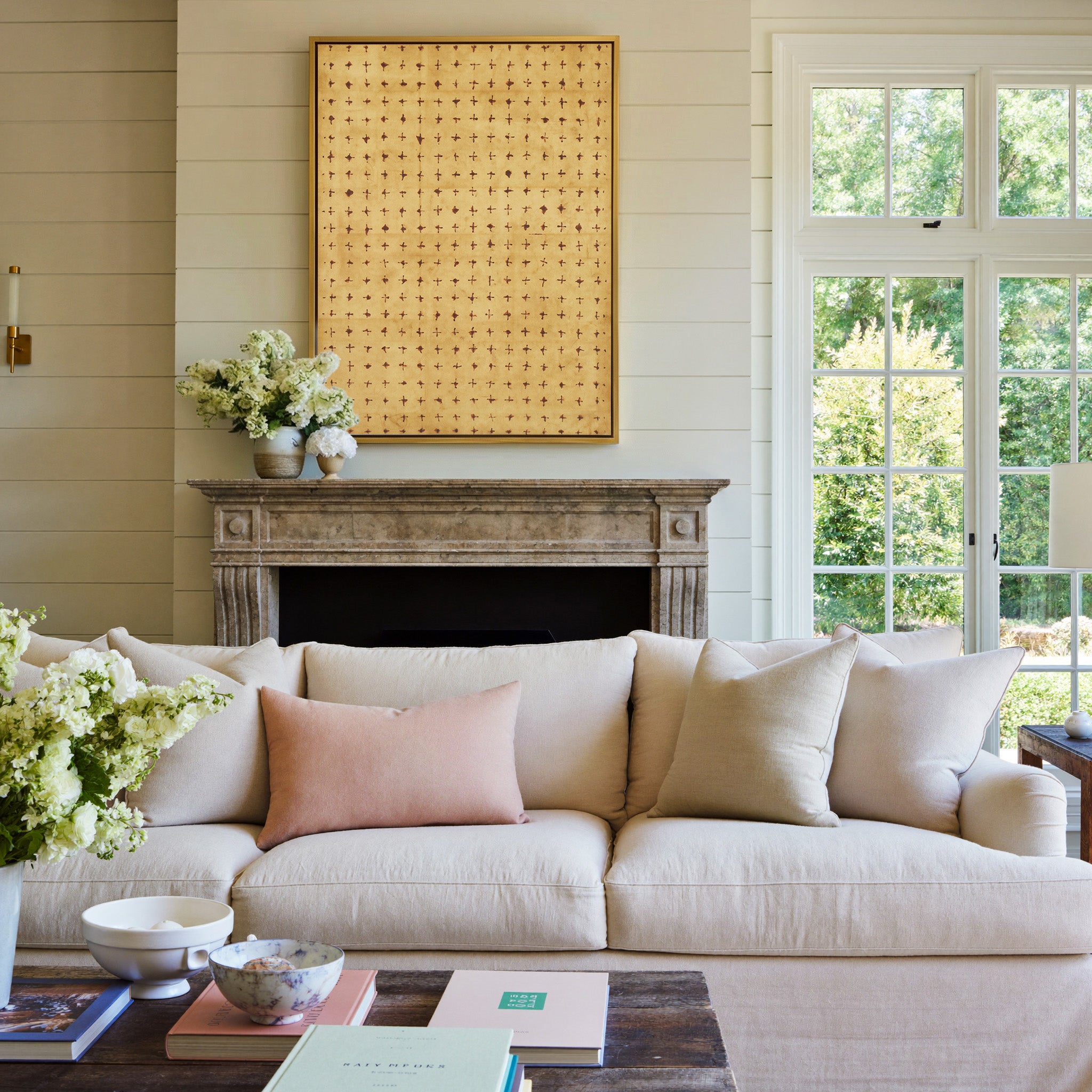 warm ochre abstract with small rust cross marks canvas wall art in a gold frame above a mantel