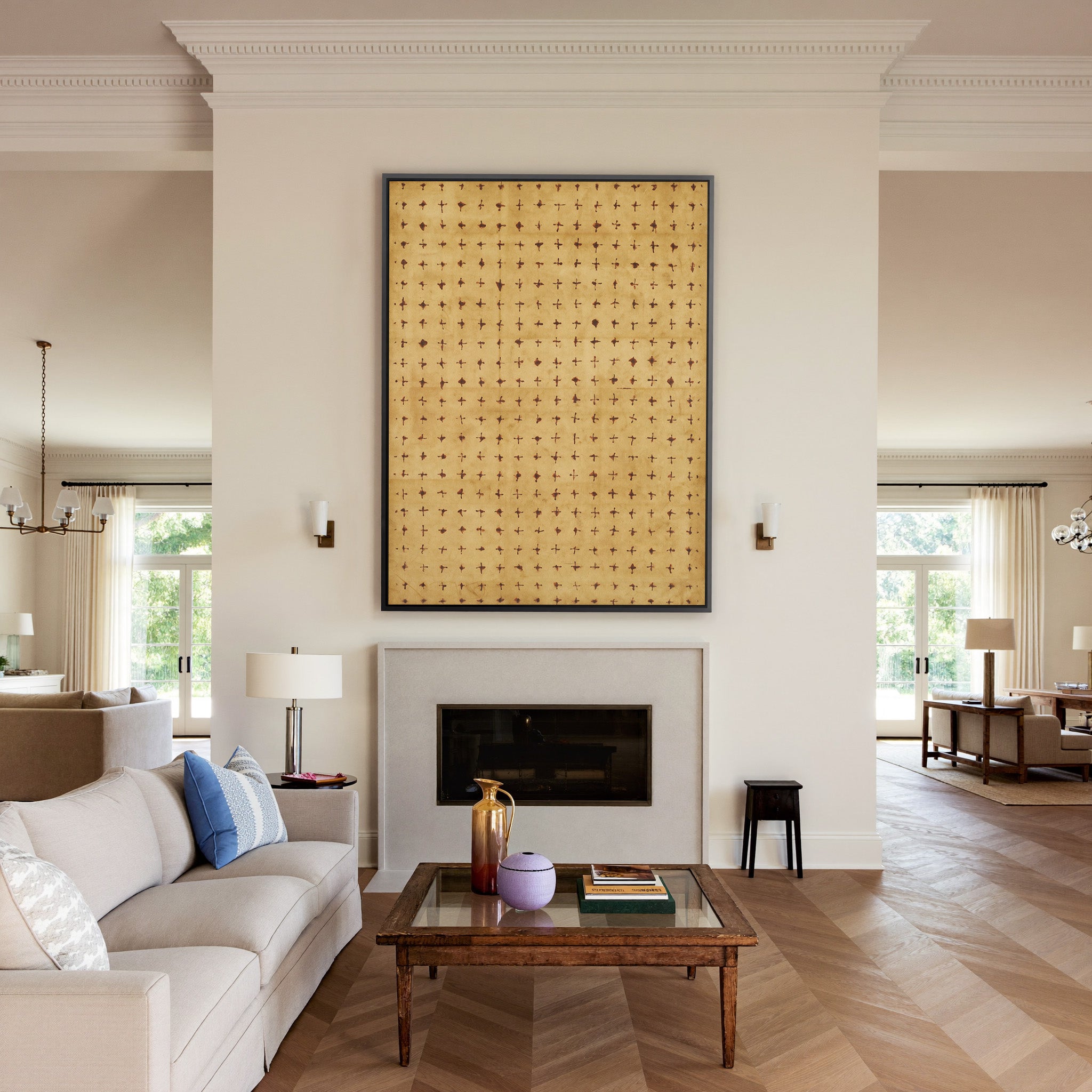 warm ochre abstract with small rust cross marks canvas wall art in a black frame above a mantel