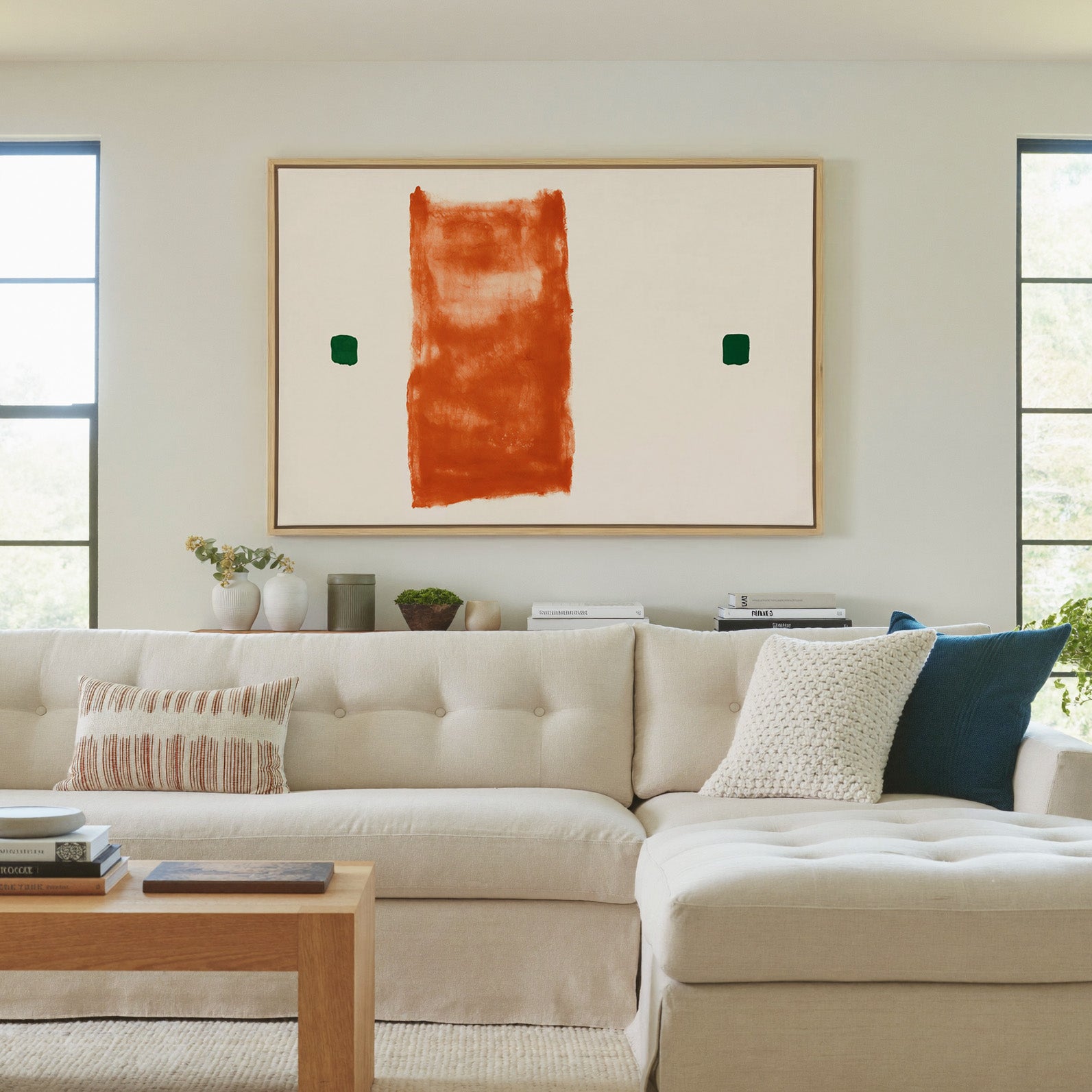 warm orange vertical block with two small green canvas wall art in a natural wood frame in a living room