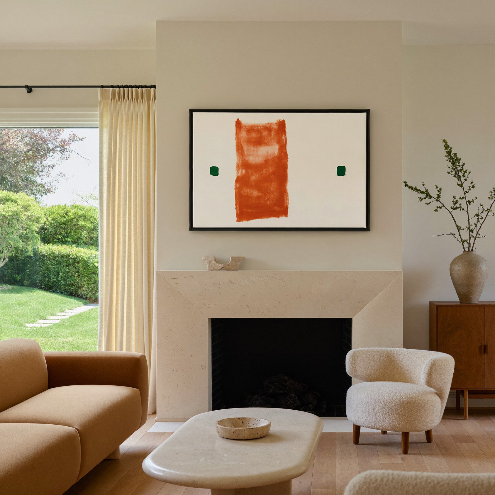 warm orange vertical block with two small green canvas wall art in a black frame above a mantel