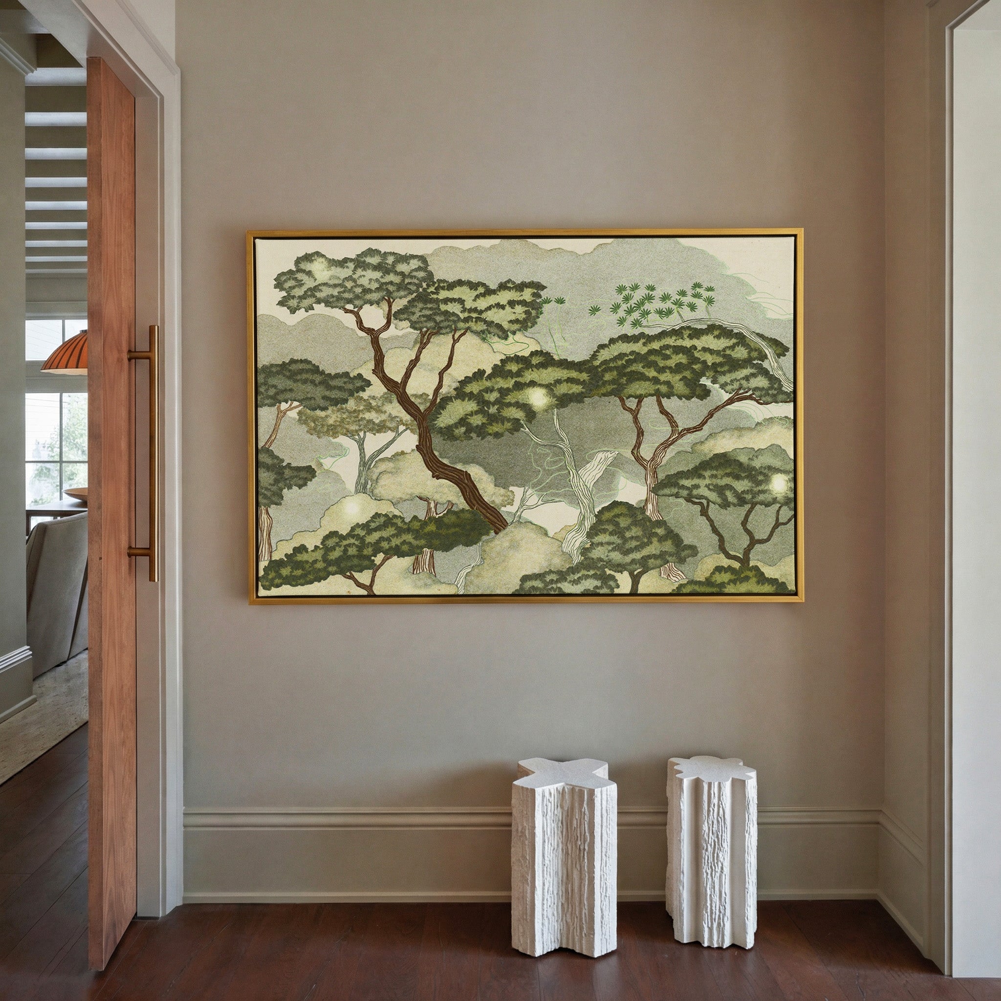 layered trees with pale green clouds and canvas wall art in a gold frame in a styled room setting