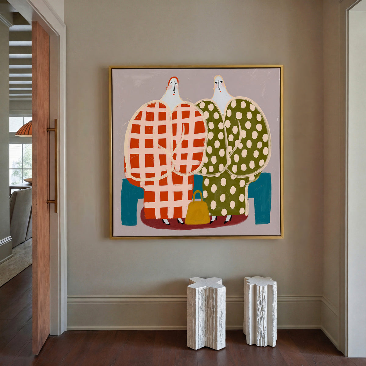 two stylized figures in check and polka dot canvas wall art in a gold frame in a styled room setting