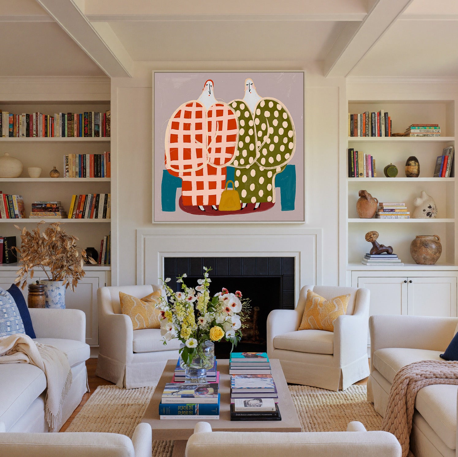 two stylized figures in check and polka dot canvas wall art in a white frame above a fireplace