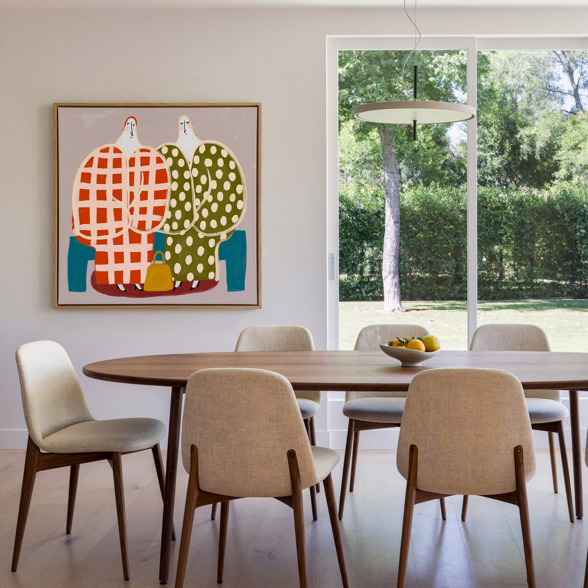 two stylized figures in check and polka dot canvas wall art in an oak frame in a dining room