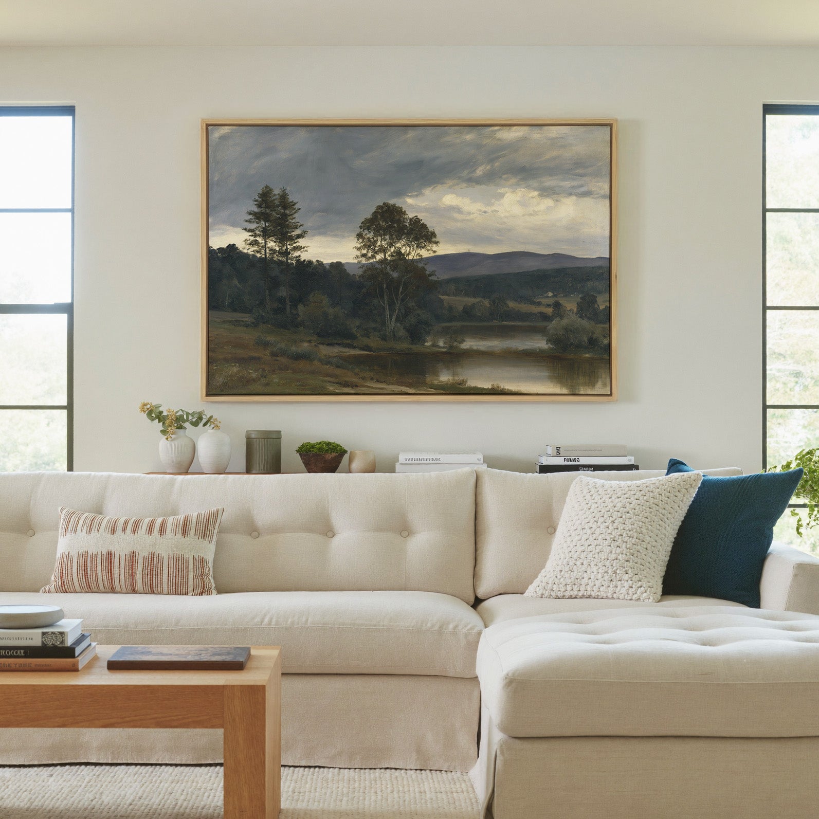 moody river landscape with trees and distant canvas wall art in a natural wood frame in a living room