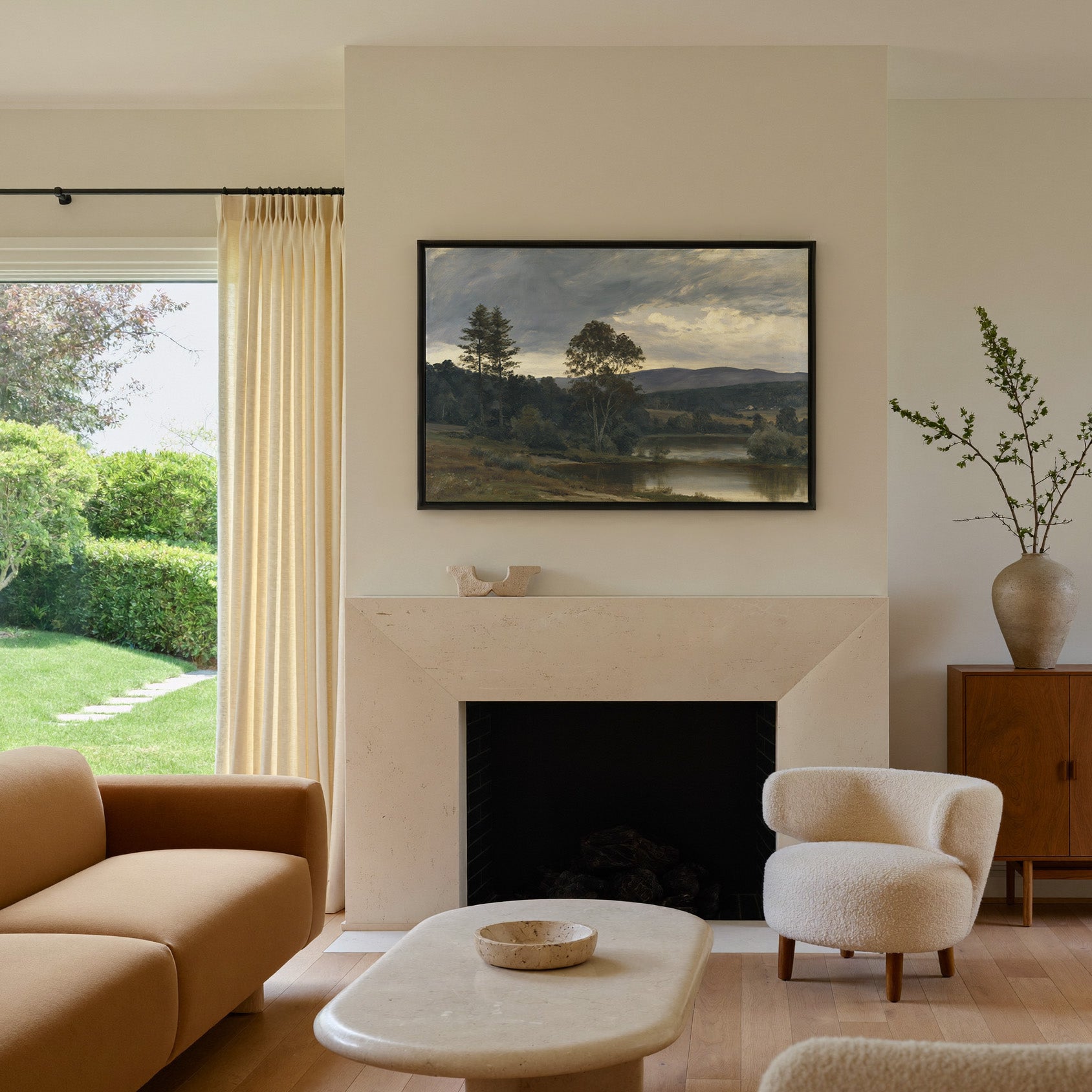 moody river landscape with trees and distant canvas wall art in a black frame above a mantel