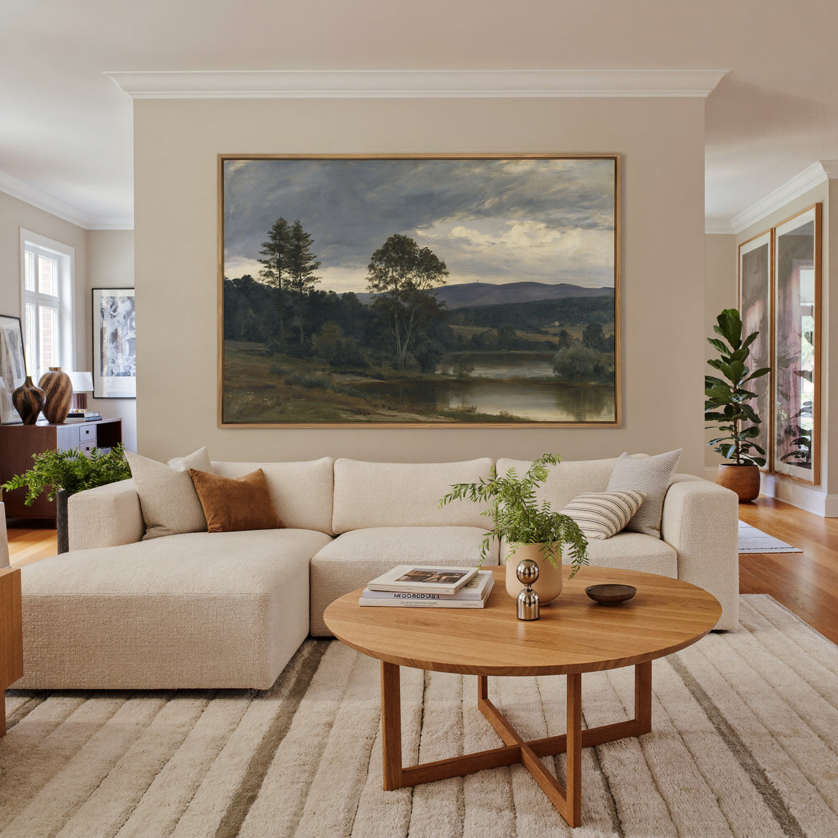 moody river landscape with trees and distant canvas wall art in an oak frame in a living room