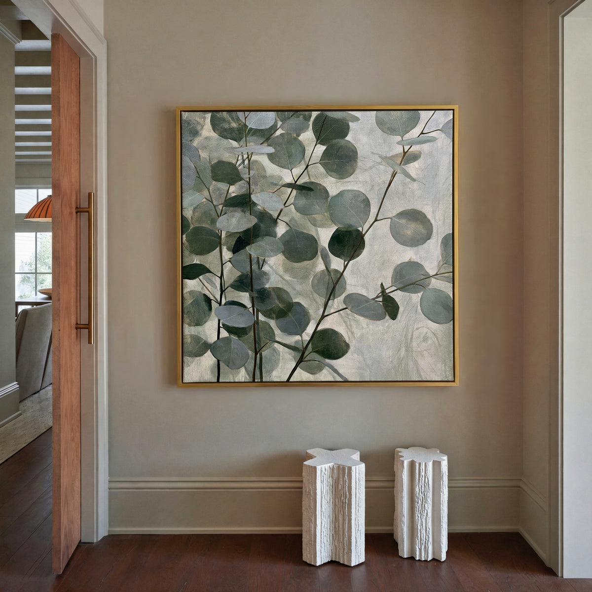 layered eucalyptus branches with rounded blue canvas wall art in a gold frame in a styled room setting
