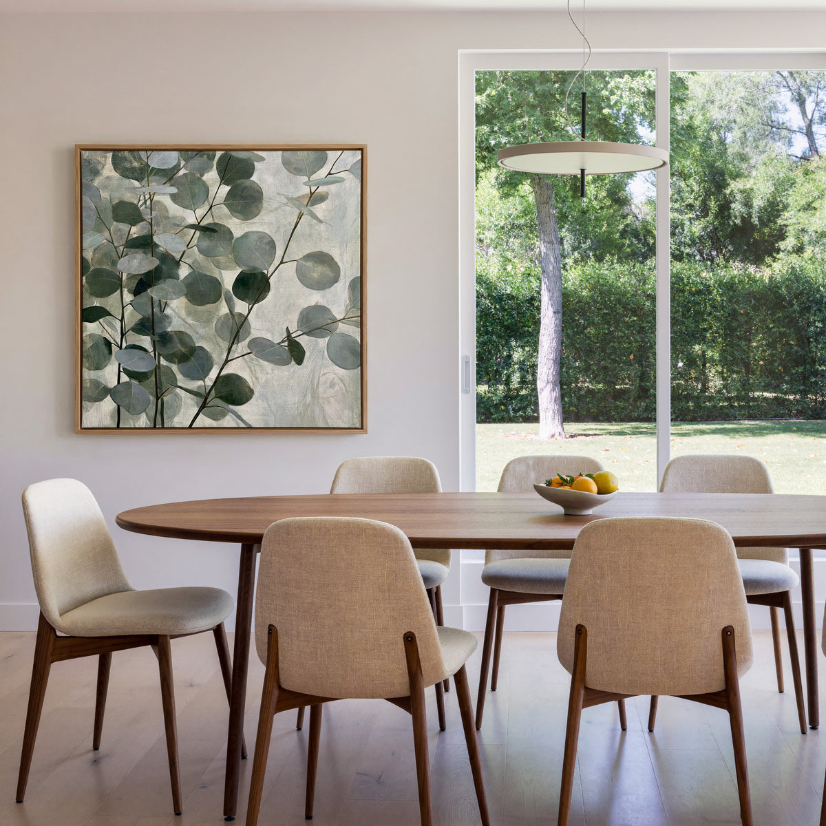layered eucalyptus branches with rounded blue canvas wall art in an oak frame in a dining room