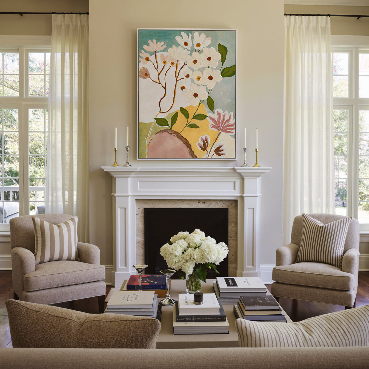soft white blossoms with green leaves on a pale canvas wall art in a white frame above a mantel