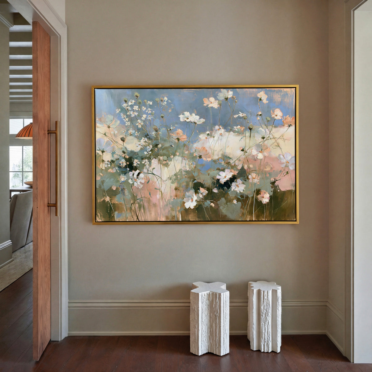 soft white and blush wildflowers under a blue canvas wall art in a gold frame in a styled room setting