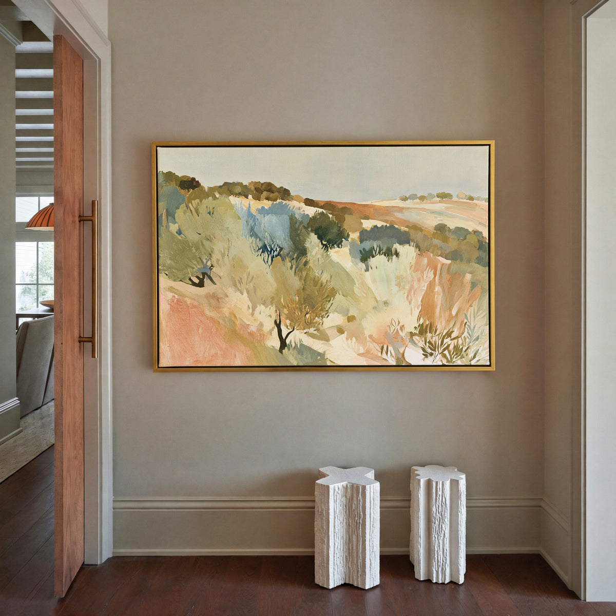 warm hillside olive orchard with pale sky and canvas wall art in a gold frame in a styled room setting