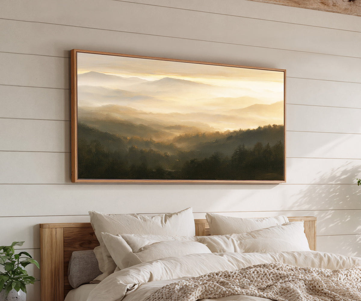 layered misty mountain landscape at sunrise canvas wall art in an oak frame above a bed