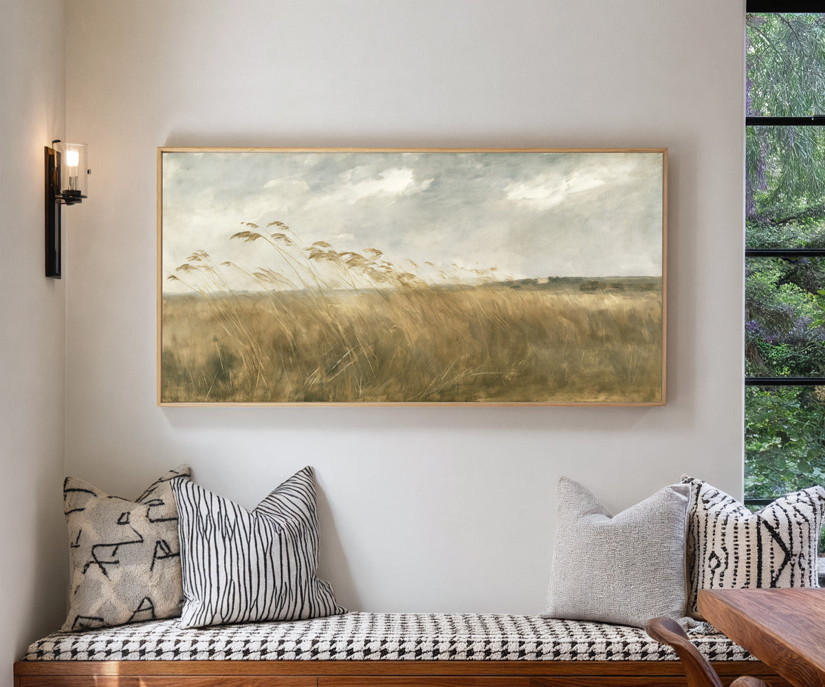 wide field of tall grasses bending in one canvas wall art in a natural wood frame in a living room