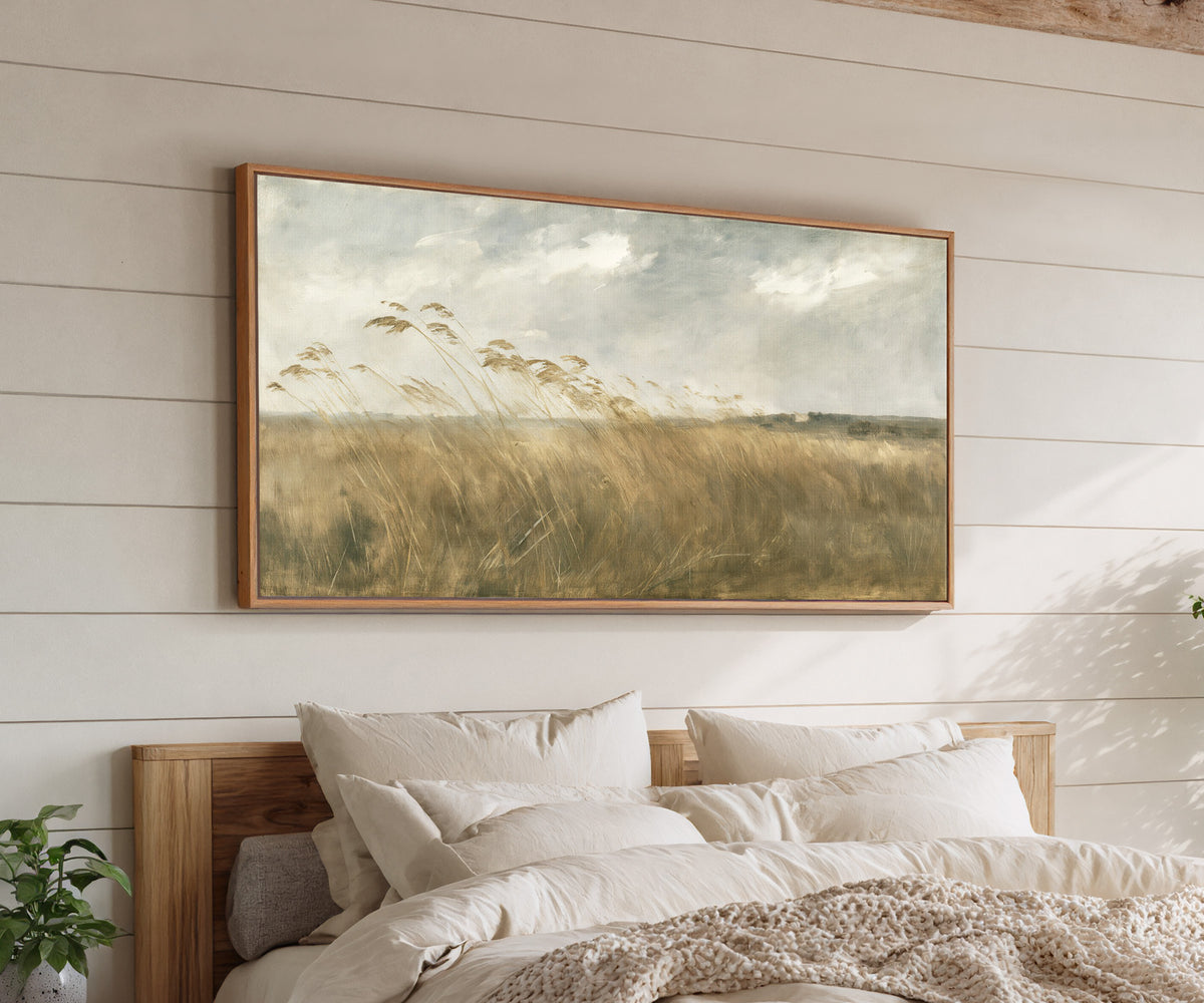 wide field of tall grasses bending in one canvas wall art in an oak frame above a bed