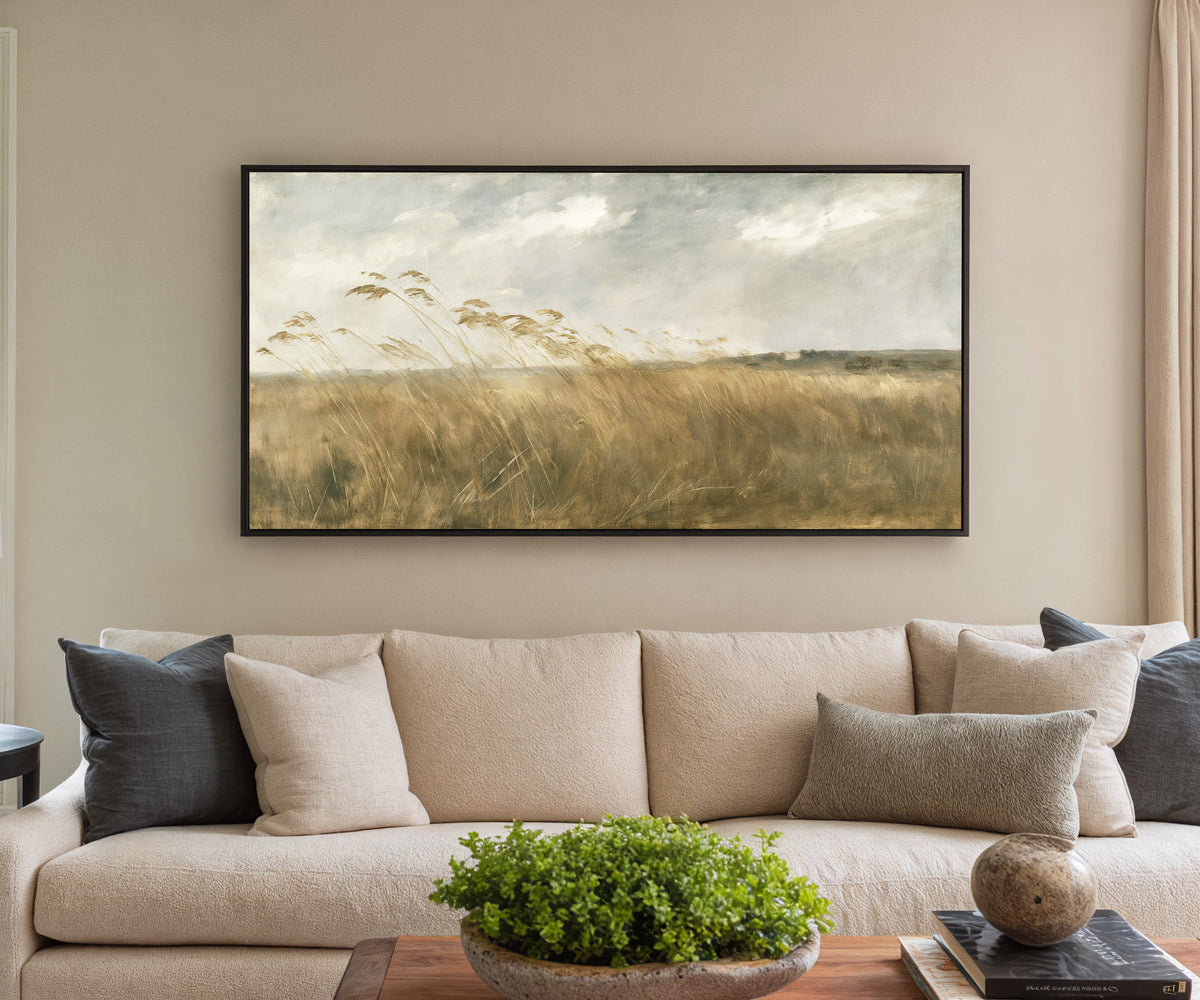 wide field of tall grasses bending in one canvas wall art in a black frame in a styled room setting